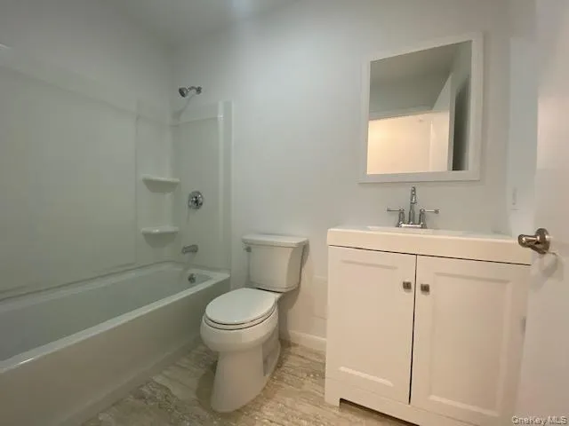 Bathroom with vanity, washtub / shower combination, and wood finished floors Bathroom with vanity, washtub / shower combination, and wood finished floors