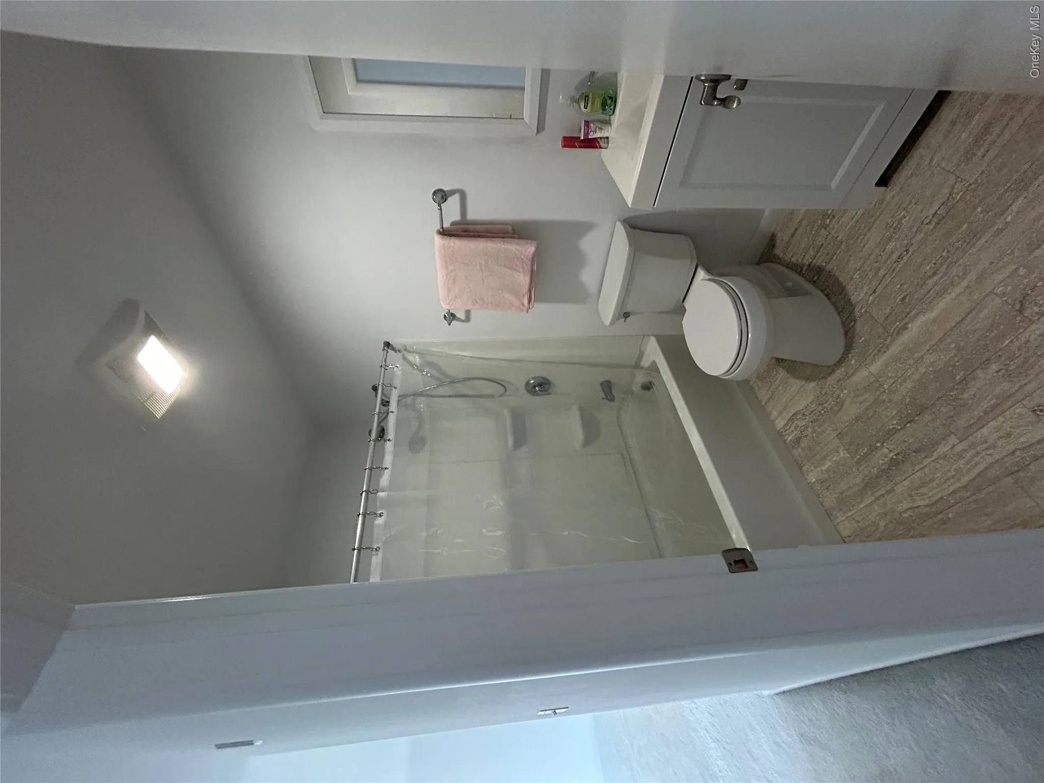 Full bathroom with shower / bathtub combination with curtain, vanity, and wood finished floors Full bathroom with shower / bathtub combination with curtain, vanity, and wood finished floors