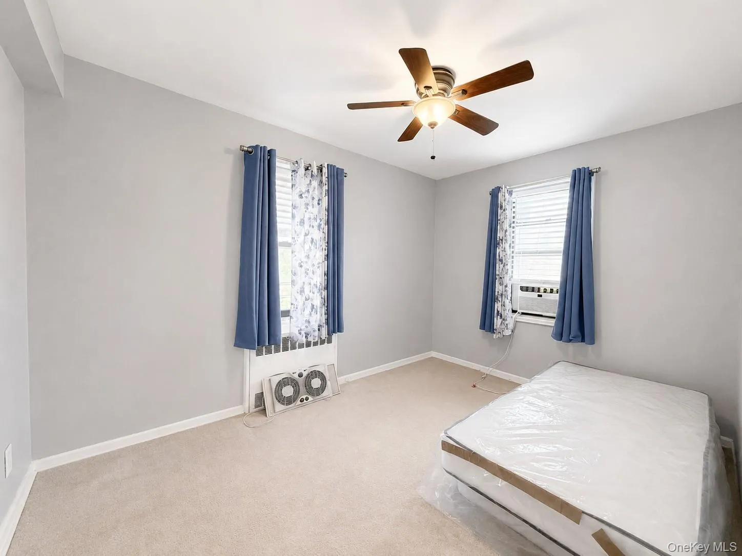 Carpeted room featuring a ceiling fan with integrated lighting, window blinds, and a window air conditioning unit Carpeted room featuring a ceiling fan with integrated lighting, window blinds, and a window air conditioning unit