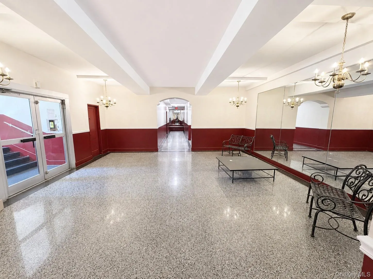 Spacious communal lobby featuring polished terrazzo flooring, large wall-mounted mirrors, and elegant brass chandeliers Spacious communal lobby featuring polished terrazzo flooring, large wall-mounted mirrors, and elegant brass chandeliers