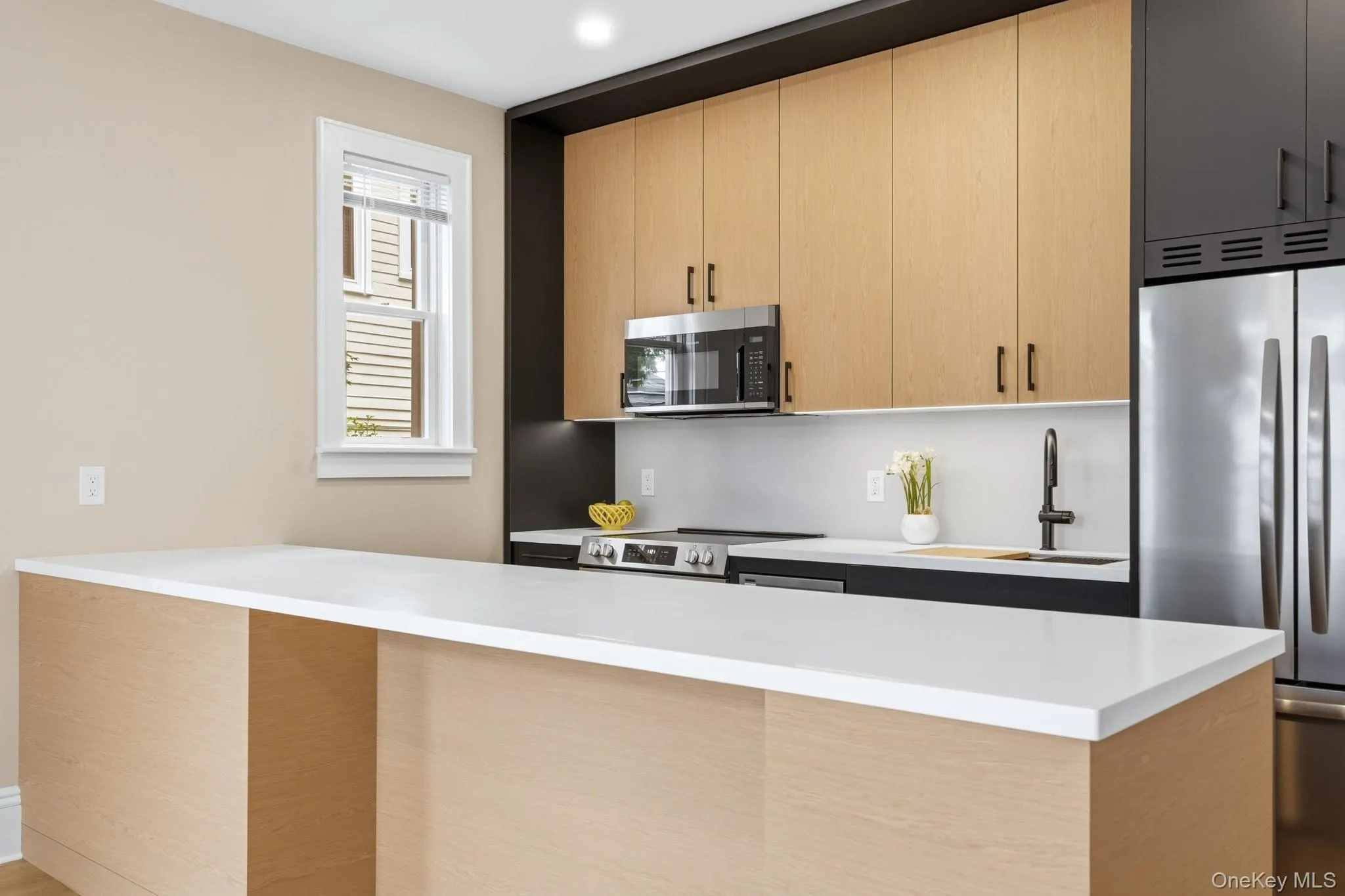 Contemporary kitchen featuring two-tone cabinetry, stainless steel appliances, white countertops, chef's sink, and light wood-finish flooring. Contemporary kitchen featuring two-tone cabinetry, stainless steel appliances, white countertops, chef's sink, and light wood-finish flooring.