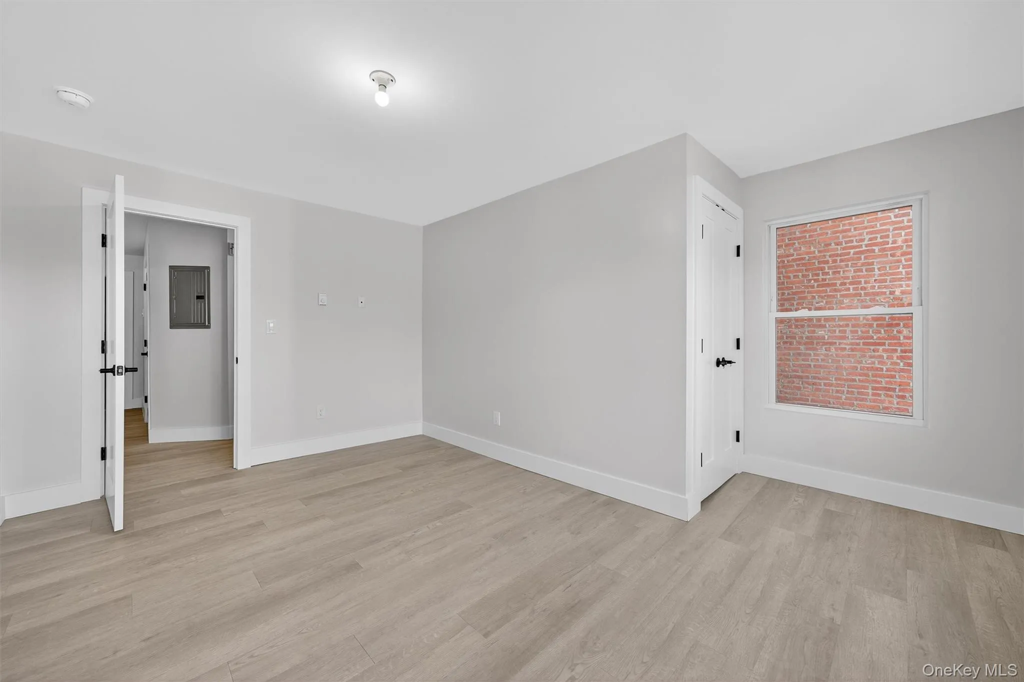 Empty room with light wood-style floors and electric panel Empty room with light wood-style floors and electric panel