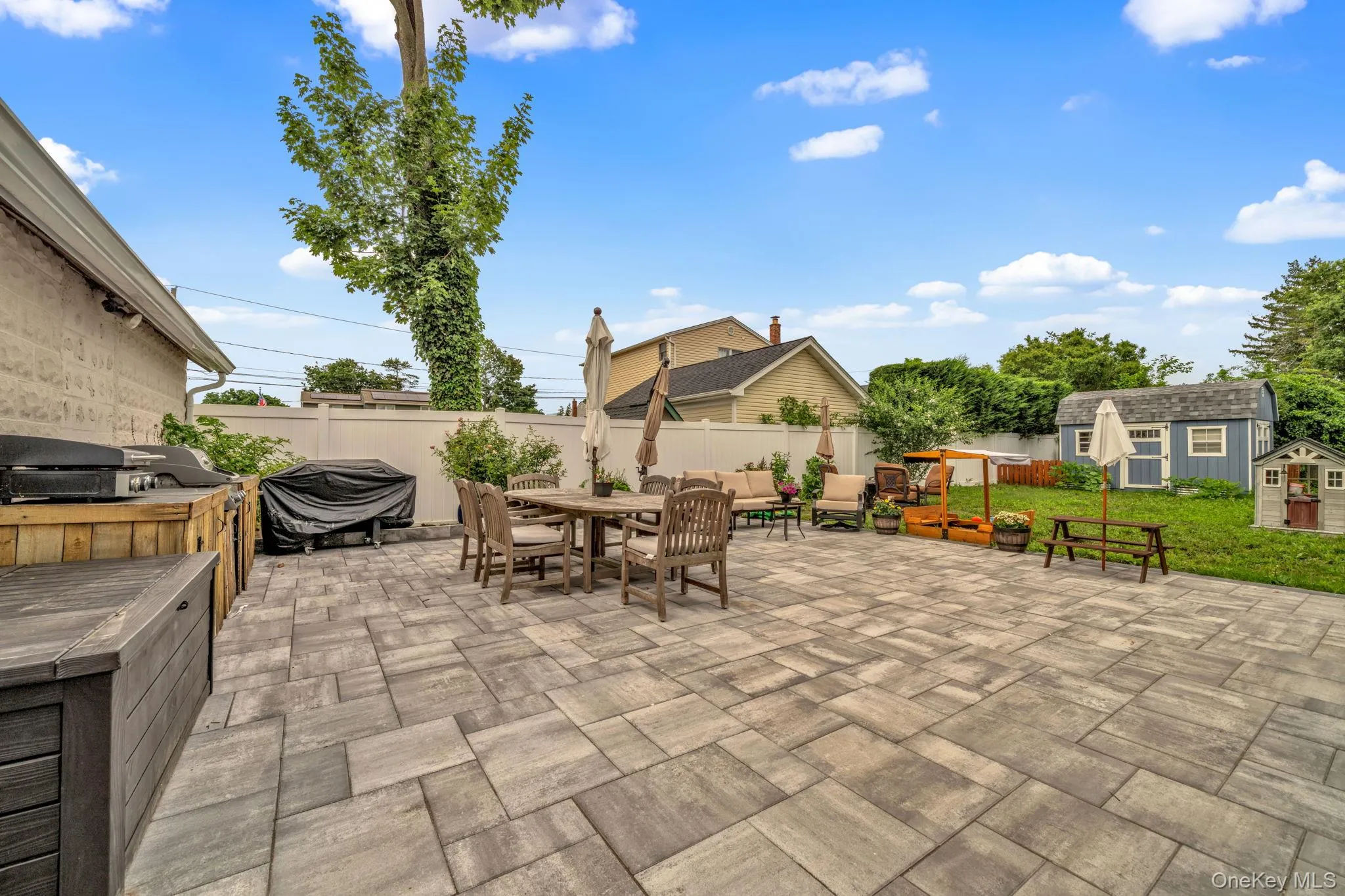 Expansive paver patio with a white privacy fence Expansive paver patio with a white privacy fence
