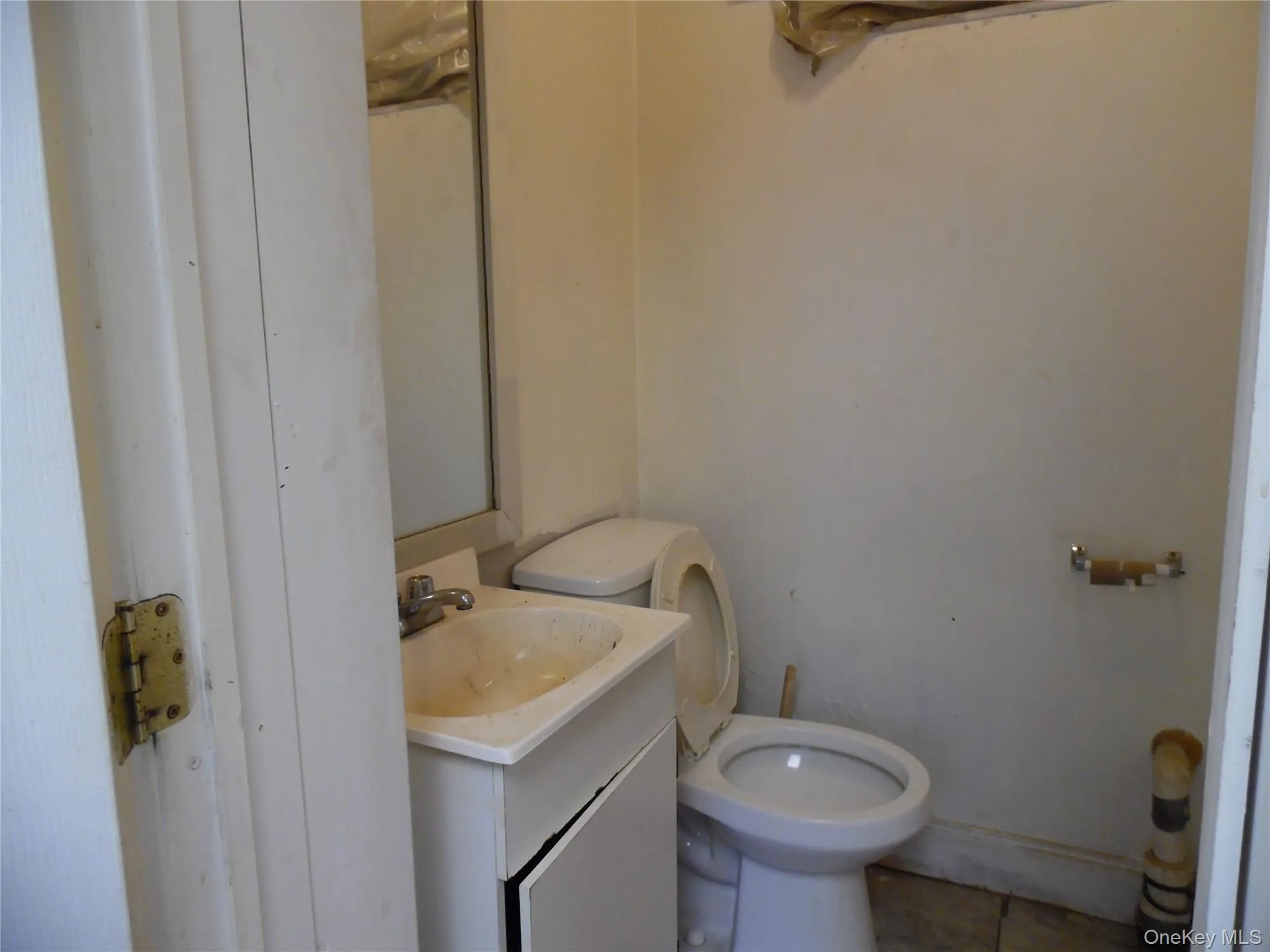 Compact bathroom featuring a white ceramic toilet, a vanity with a drop-in sink, and a wall-mounted mirror Compact bathroom featuring a white ceramic toilet, a vanity with a drop-in sink, and a wall-mounted mirror
