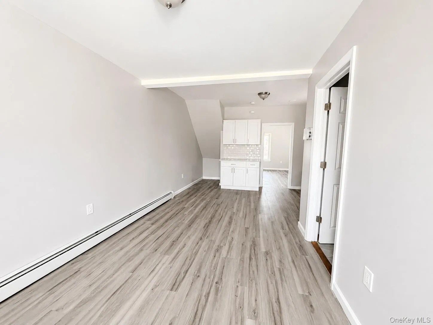 Open concept living area featuring wood-finish flooring, light gray wall tones, and white baseboards Open concept living area featuring wood-finish flooring, light gray wall tones, and white baseboards