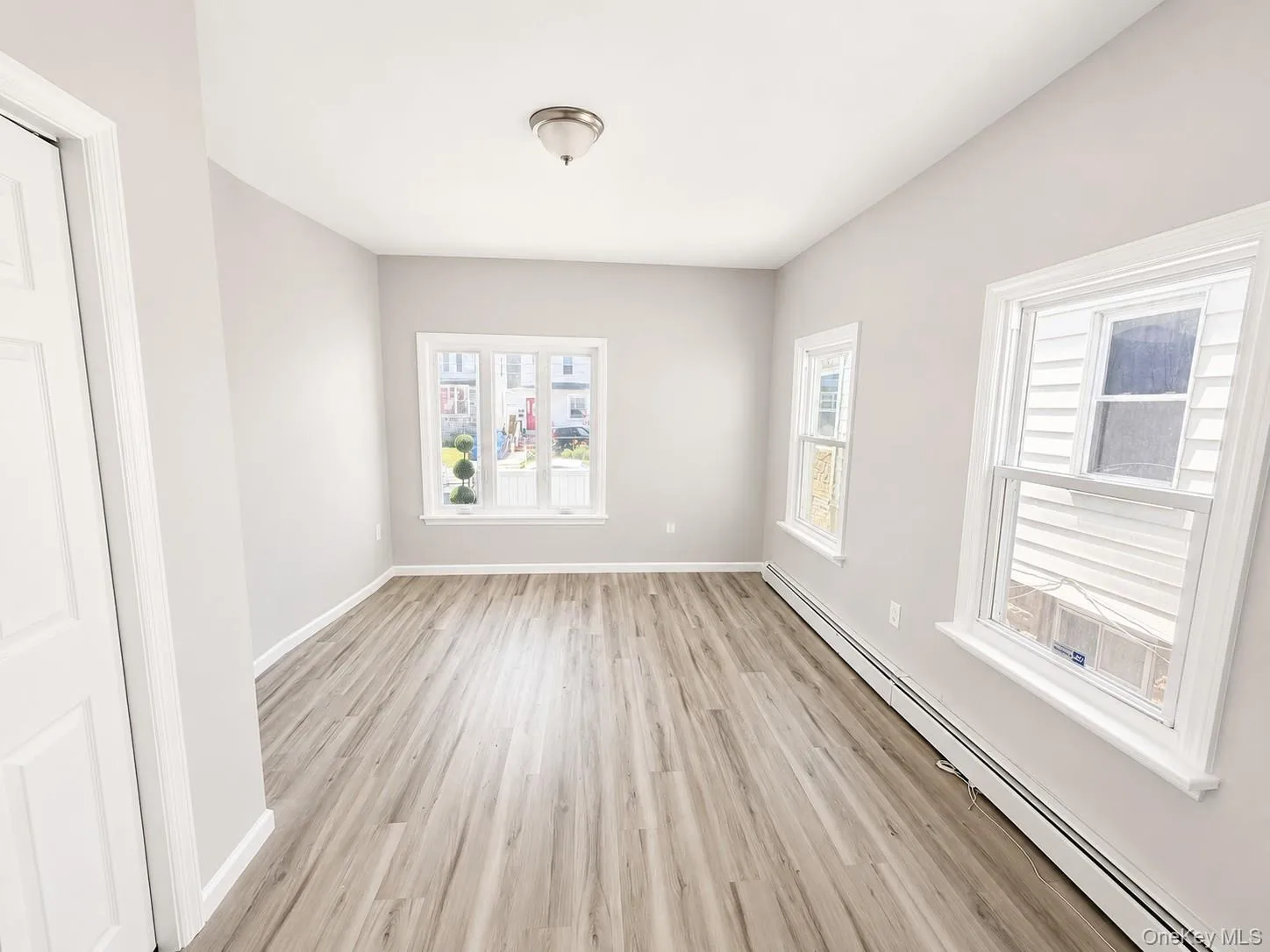 Bedroom featuring wood-finish flooring, light gray wall tones, and white baseboards Bedroom featuring wood-finish flooring, light gray wall tones, and white baseboards