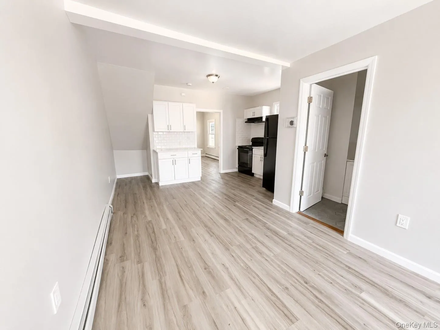 Open concept living area featuring wood-finish flooring, light gray wall tones, and white baseboards Open concept living area featuring wood-finish flooring, light gray wall tones, and white baseboards
