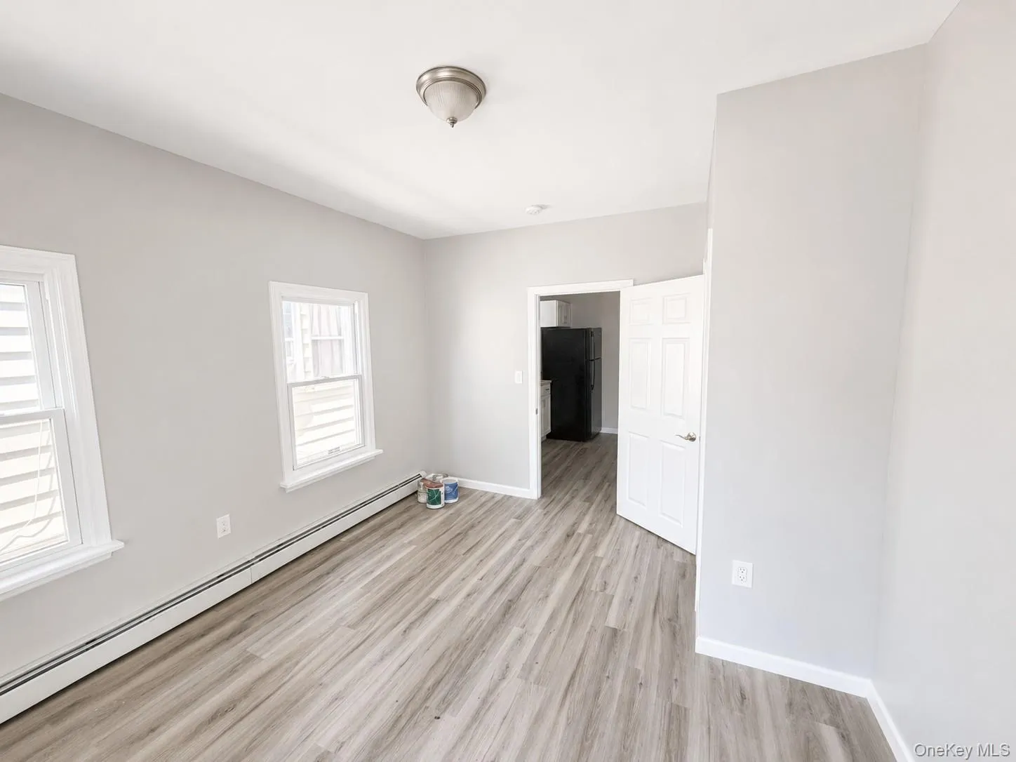 Bedroom featuring wood-finish flooring, light gray wall tones, and white baseboards Bedroom featuring wood-finish flooring, light gray wall tones, and white baseboards