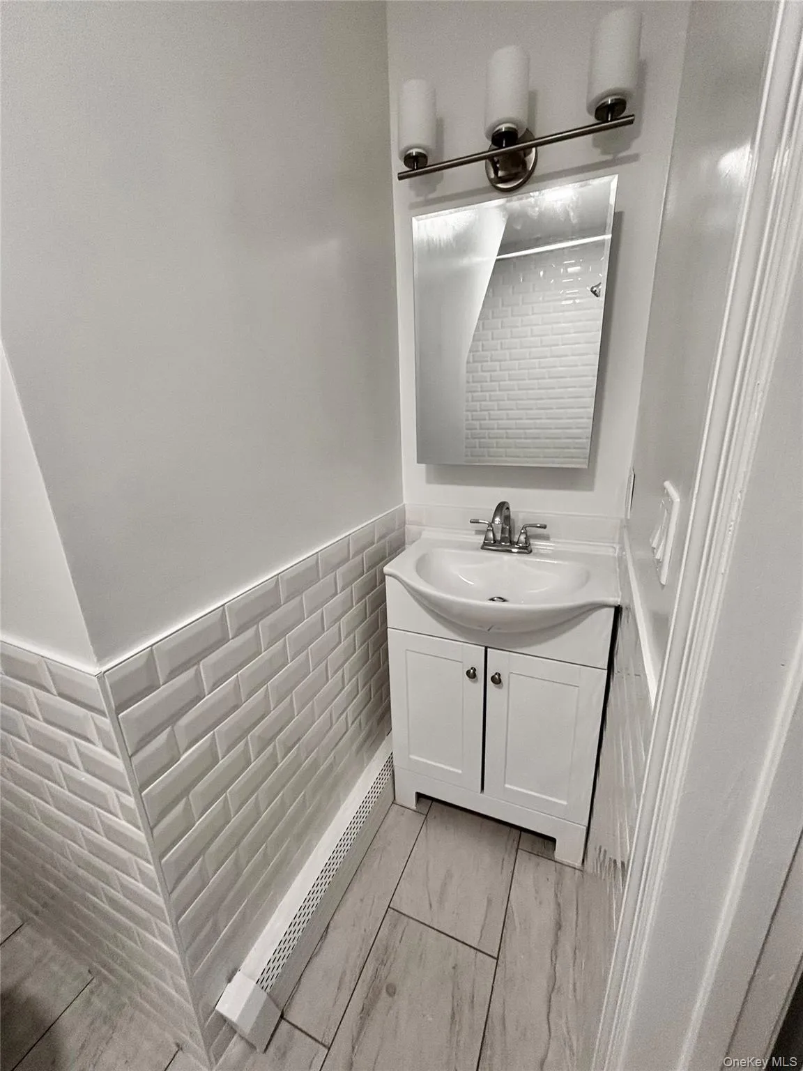 Bathroom featuring vanity, wainscoting, and marble finish floors Bathroom featuring vanity, wainscoting, and marble finish floors