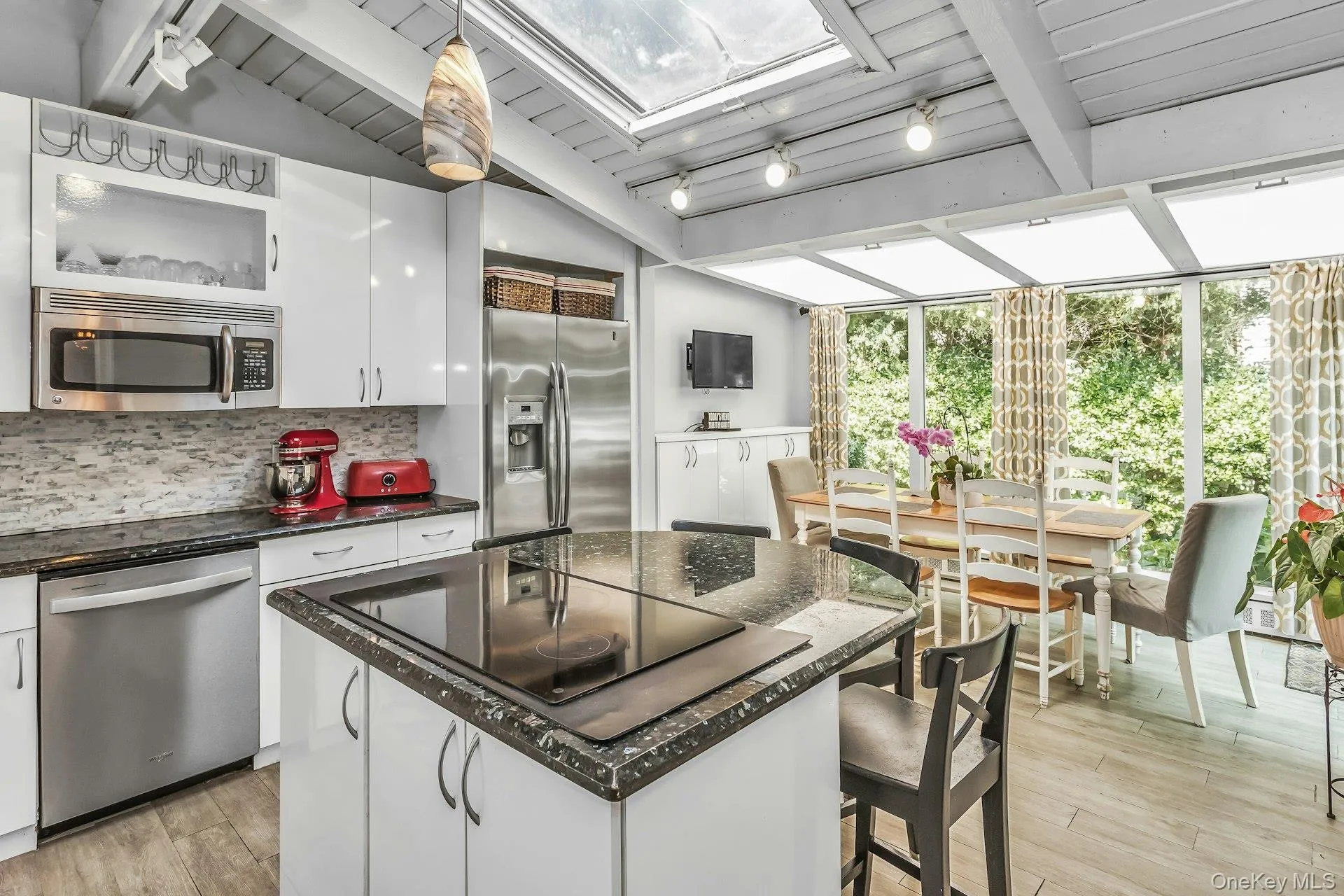 Kitchen featuring white cabinetry, stainless steel appliances, a center island with an integrated cooktop, and granite countertops EIK w/ abundance of light! Kitchen featuring white cabinetry, stainless steel appliances, a center island with an integrated cooktop, and granite countertops EIK w/ abundance of light!
