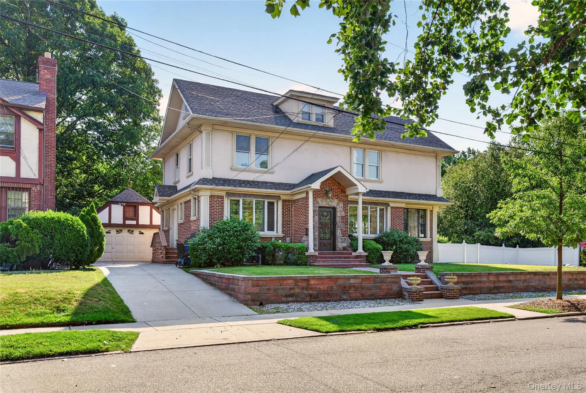 Two-story residence featuring a brick and stucco exterior, prominent front porch with columns, a multi-car driveway, and a detached two-car garage Two-story residence featuring a brick and stucco exterior, prominent front porch with columns, a multi-car driveway, and a detached two-car garage
