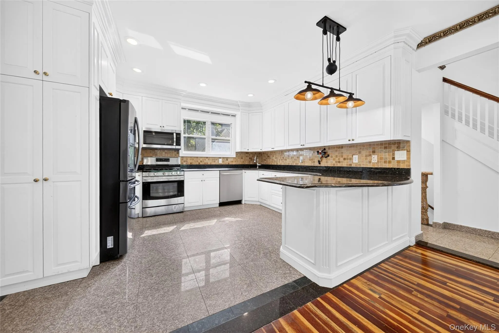 White kitchen cabinetry featuring a mosaic tile backsplash and dark countertops White kitchen cabinetry featuring a mosaic tile backsplash and dark countertops