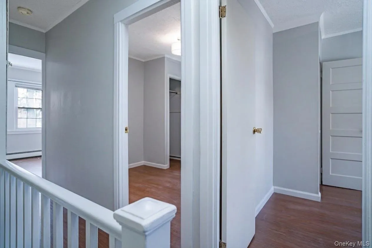 Upper-level landing featuring light gray walls, white trim, and wood-finish flooring Upper-level landing featuring light gray walls, white trim, and wood-finish flooring