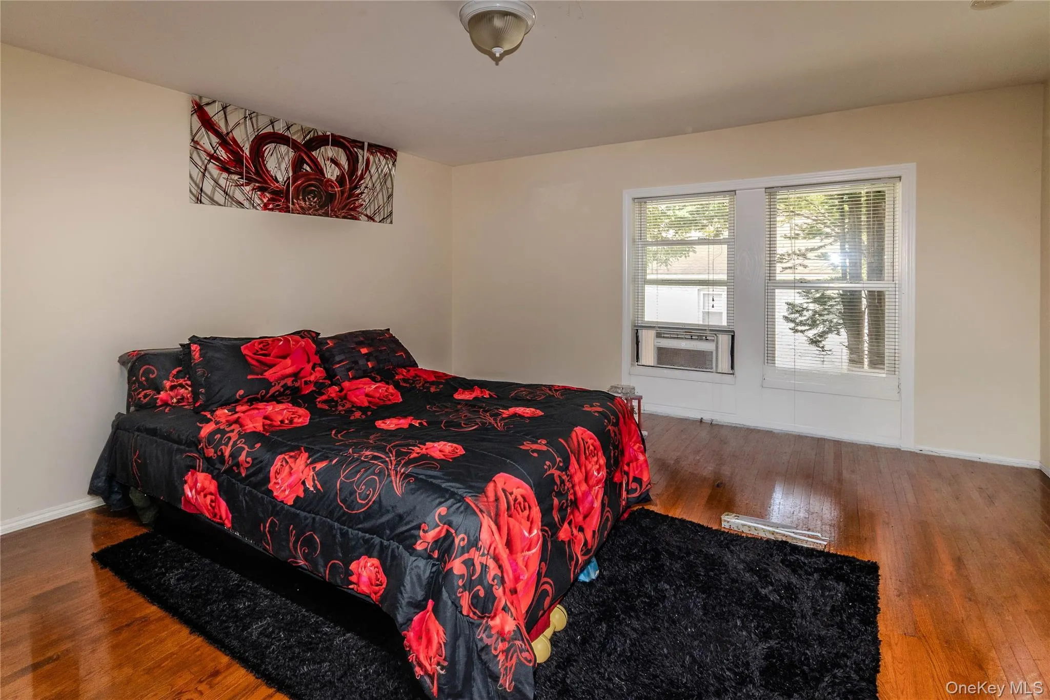 Primary bedroom with hardwood floors and large window Primary bedroom with hardwood floors and large window
