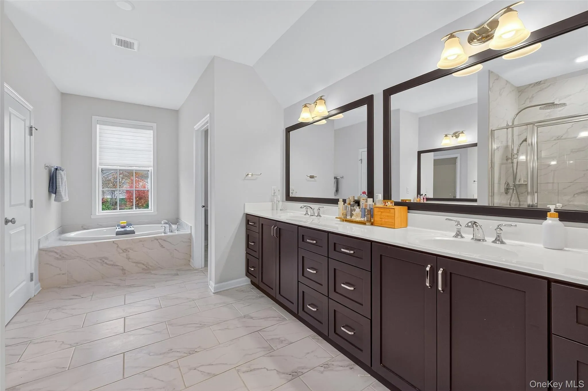 Primary bath w/light marble finish floors with a double vanity Primary bath w/light marble finish floors with a double vanity