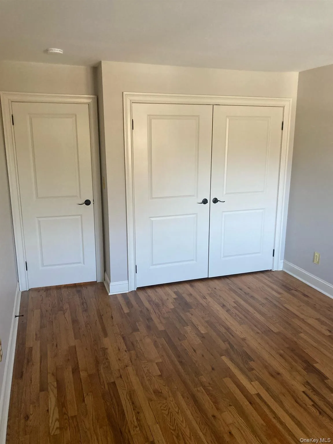 Unfurnished bedroom with dark wood-type flooring and a closet Unfurnished bedroom with dark wood-type flooring and a closet