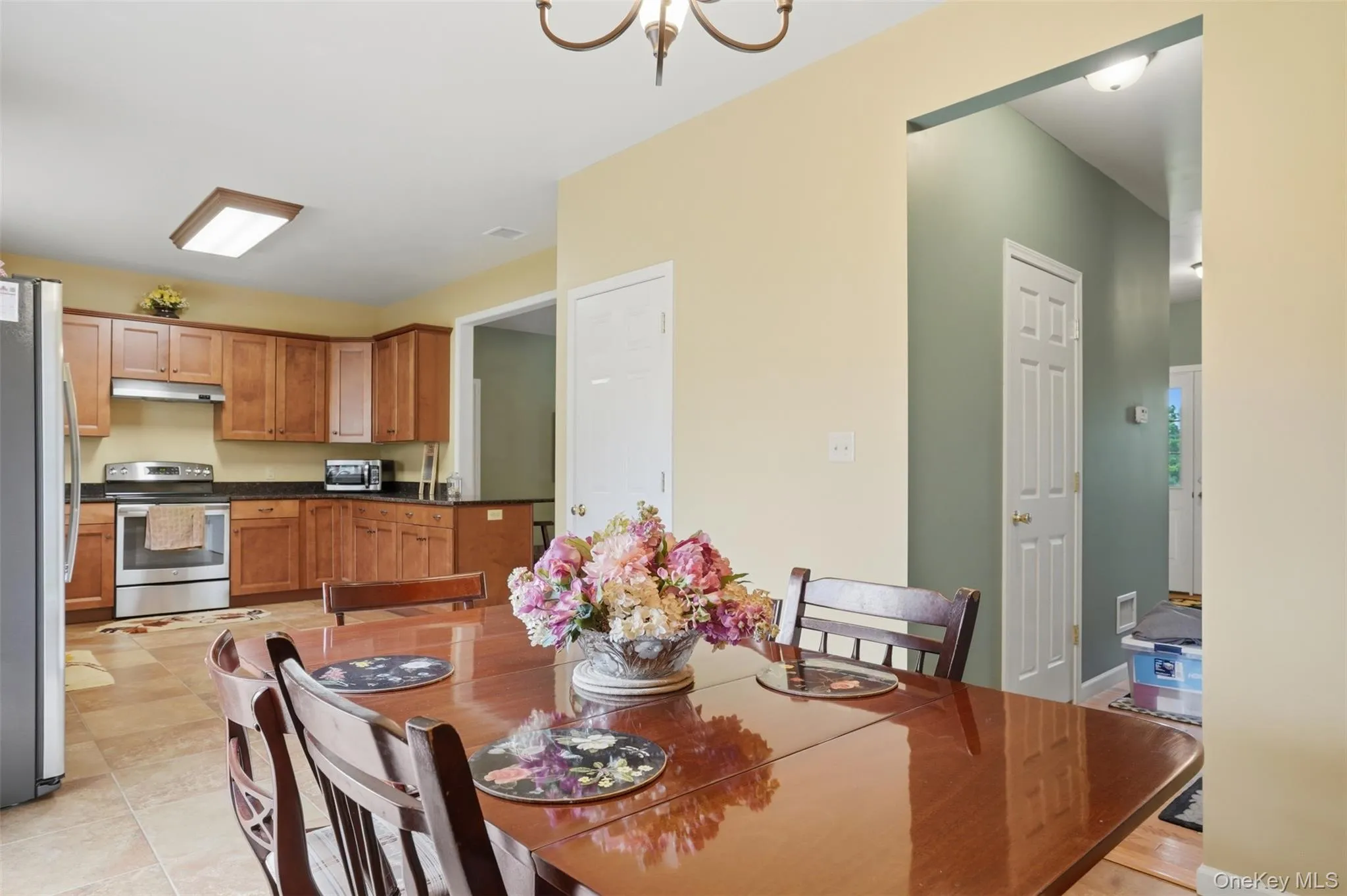 Kitchen with wood cabinetry, stainless steel appliances, and dark countertops Kitchen with wood cabinetry, stainless steel appliances, and dark countertops