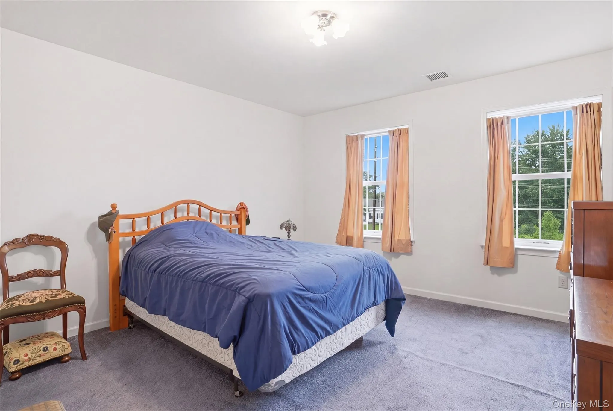 Light-filled interior space featuring two large windows, neutral wall tones, and gray carpeting Light-filled interior space featuring two large windows, neutral wall tones, and gray carpeting