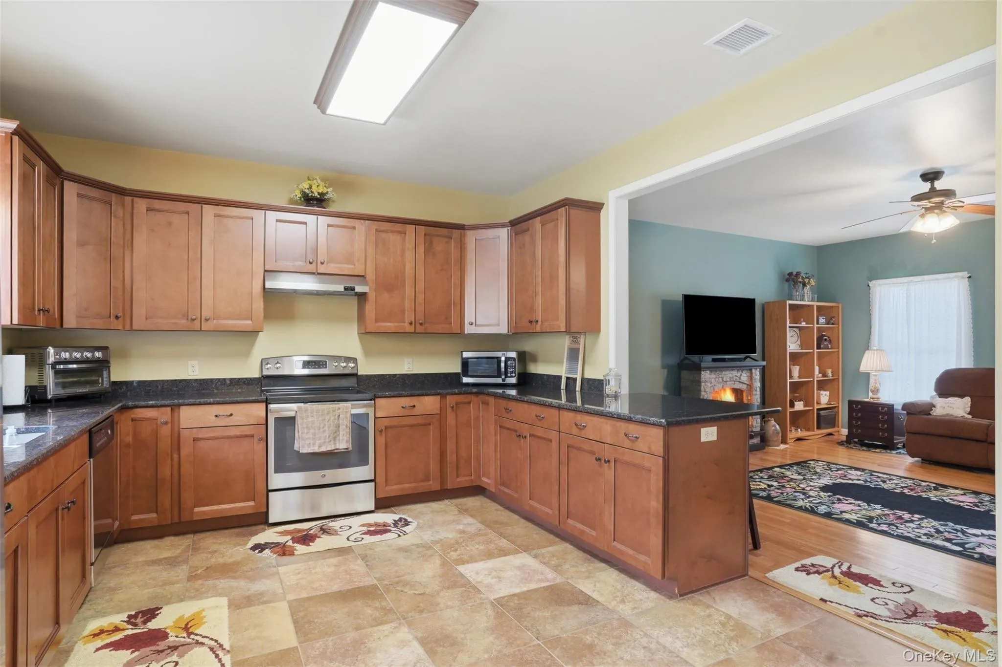 Kitchen featuring extensive wood cabinetry, dark countertops, and tile flooring Kitchen featuring extensive wood cabinetry, dark countertops, and tile flooring