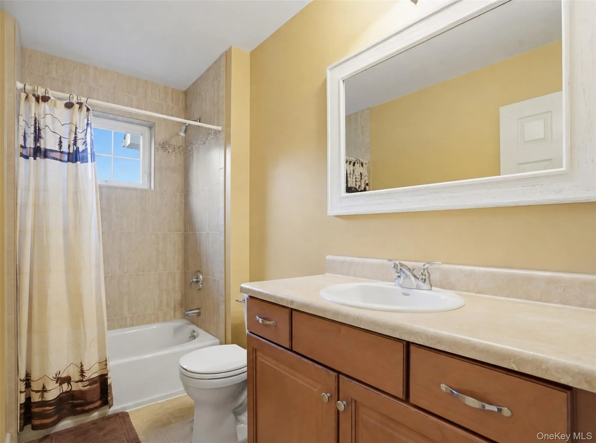 Bathroom featuring a vanity with wood-finish cabinetry, a single basin sink, and a light-colored countertop Bathroom featuring a vanity with wood-finish cabinetry, a single basin sink, and a light-colored countertop