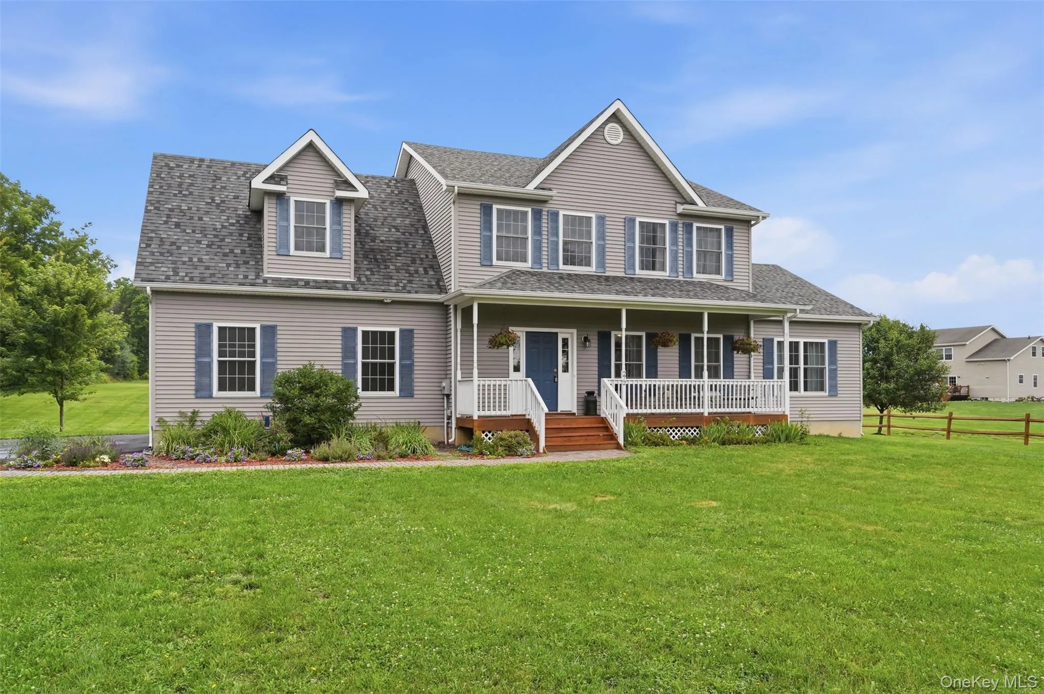 Colonial-style residence featuring light gray siding, dark blue window shutters, a covered front porch with white railings, a blue entry door, and a shingled roof Colonial-style residence featuring light gray siding, dark blue window shutters, a covered front porch with white railings, a blue entry door, and a shingled roof