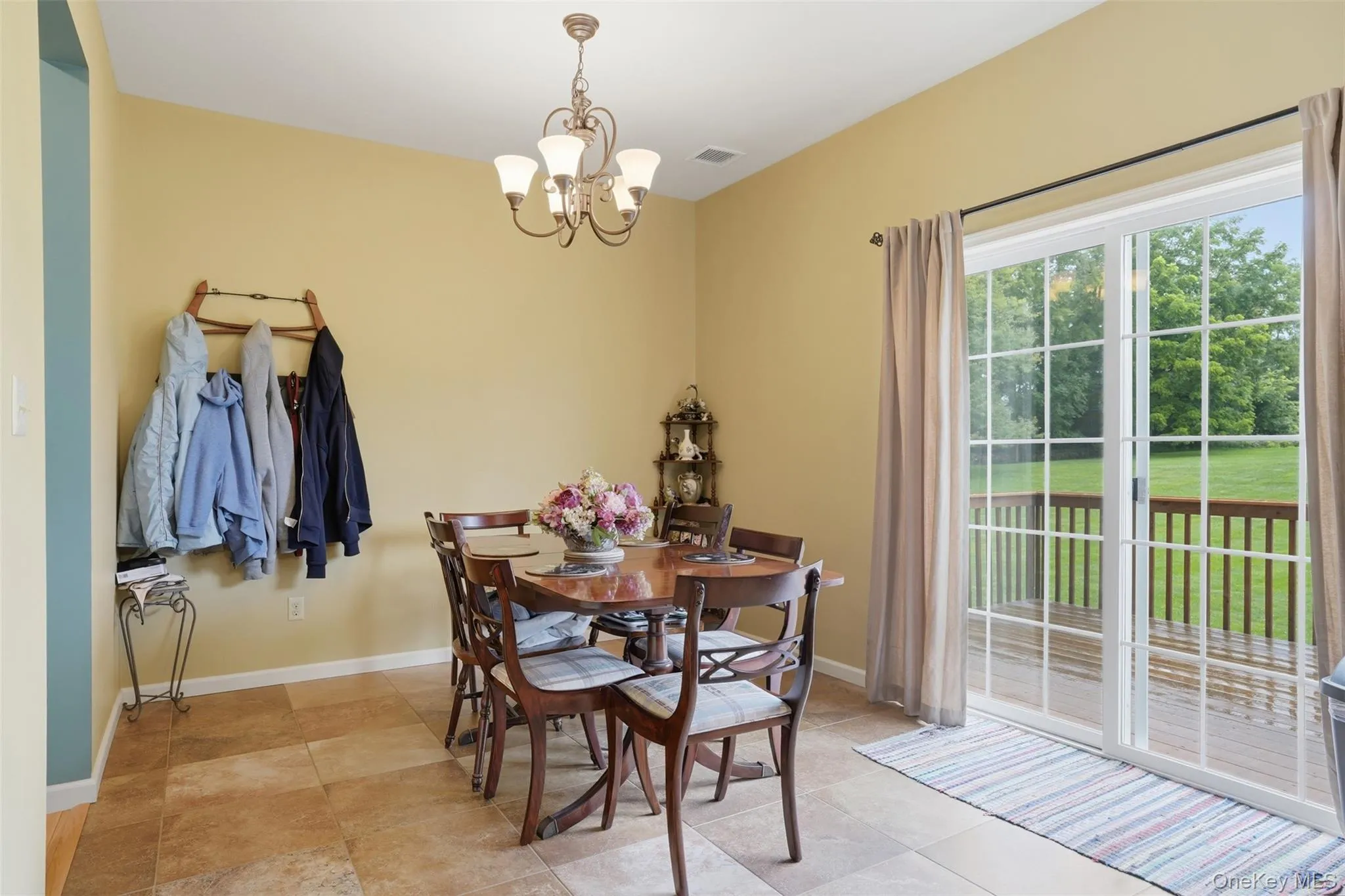 Dining area featuring tile flooring, a decorative chandelier, and a sliding glass door leading to an outdoor deck Dining area featuring tile flooring, a decorative chandelier, and a sliding glass door leading to an outdoor deck