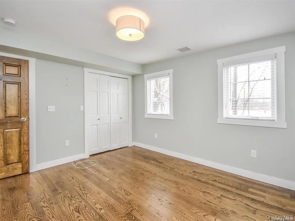 Unfurnished bedroom featuring wood finished floors and a closet Unfurnished bedroom featuring wood finished floors and a closet