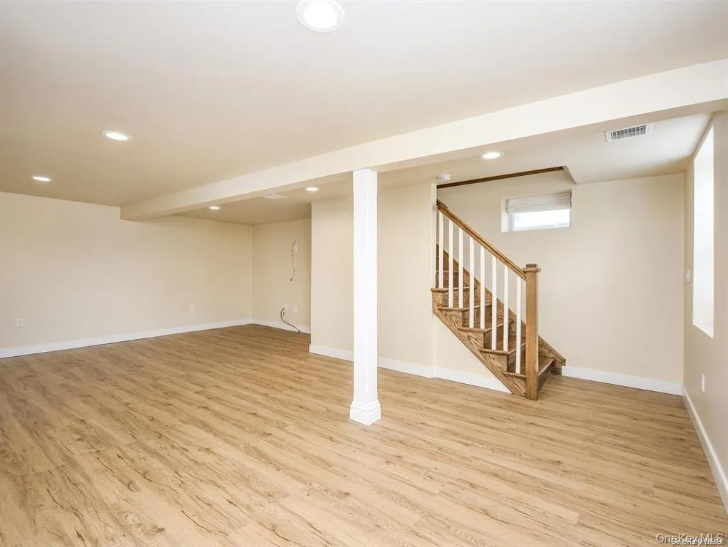 Basement with light wood-style flooring, recessed lighting, and stairs Basement with light wood-style flooring, recessed lighting, and stairs