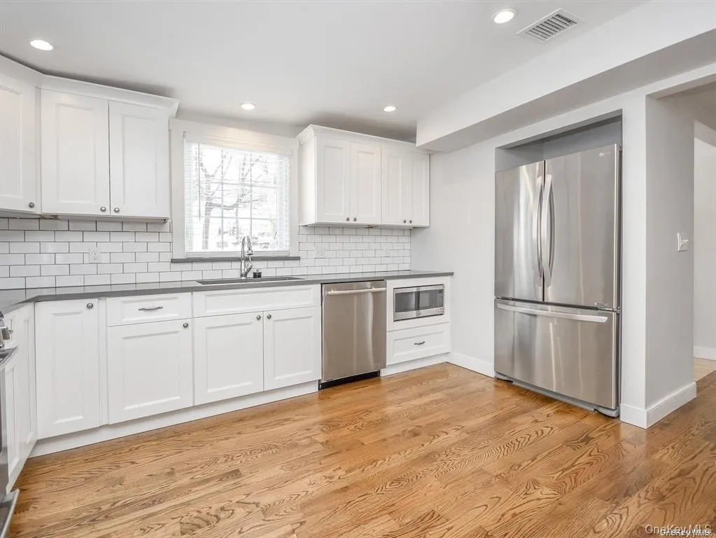 Kitchen with stainless steel appliances, white cabinetry, dark countertops, recessed lighting, and decorative backsplash Kitchen with stainless steel appliances, white cabinetry, dark countertops, recessed lighting, and decorative backsplash