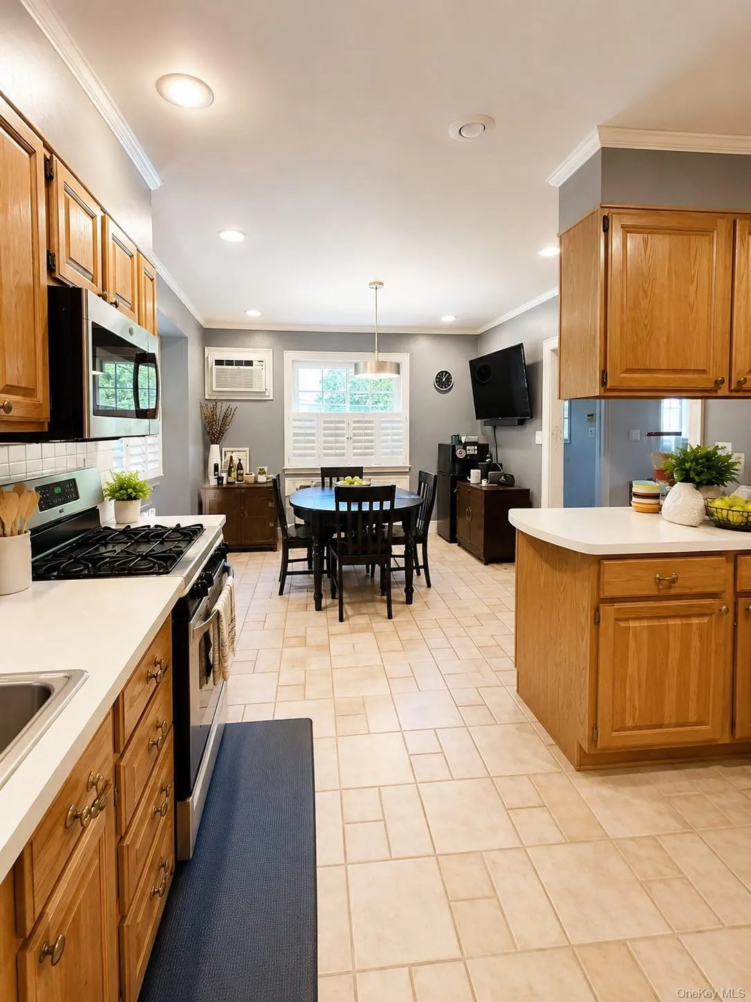 Open-concept kitchen and dining area featuring light wood cabinetry, light-toned tile flooring, and white countertops Open-concept kitchen and dining area featuring light wood cabinetry, light-toned tile flooring, and white countertops