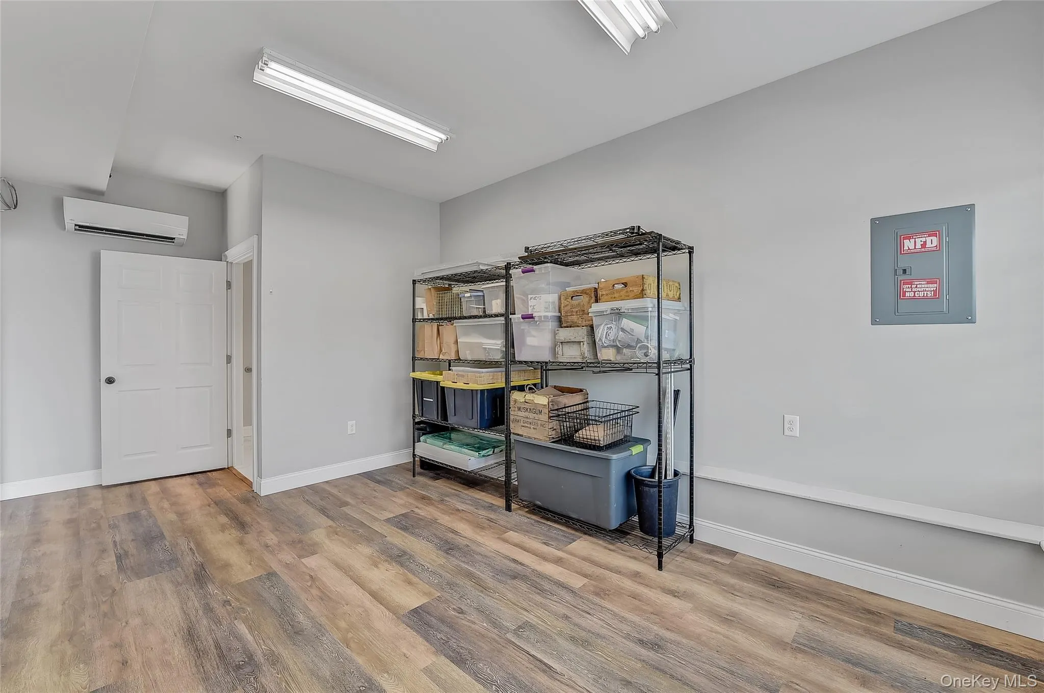 Storage room featuring electric panel and a wall mounted air conditioner Storage room featuring electric panel and a wall mounted air conditioner