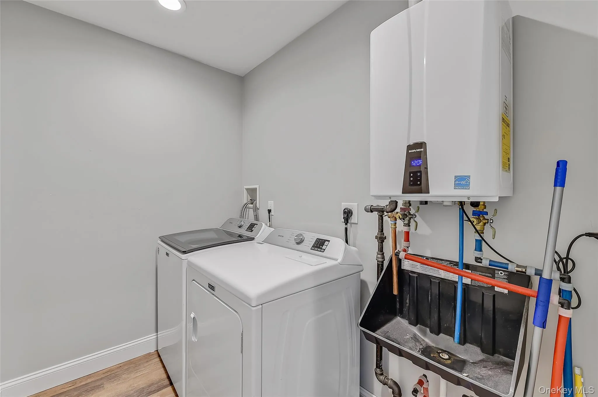 Laundry room with tankless water heater, light wood-type flooring, recessed lighting, and independent washer and dryer Laundry room with tankless water heater, light wood-type flooring, recessed lighting, and independent washer and dryer