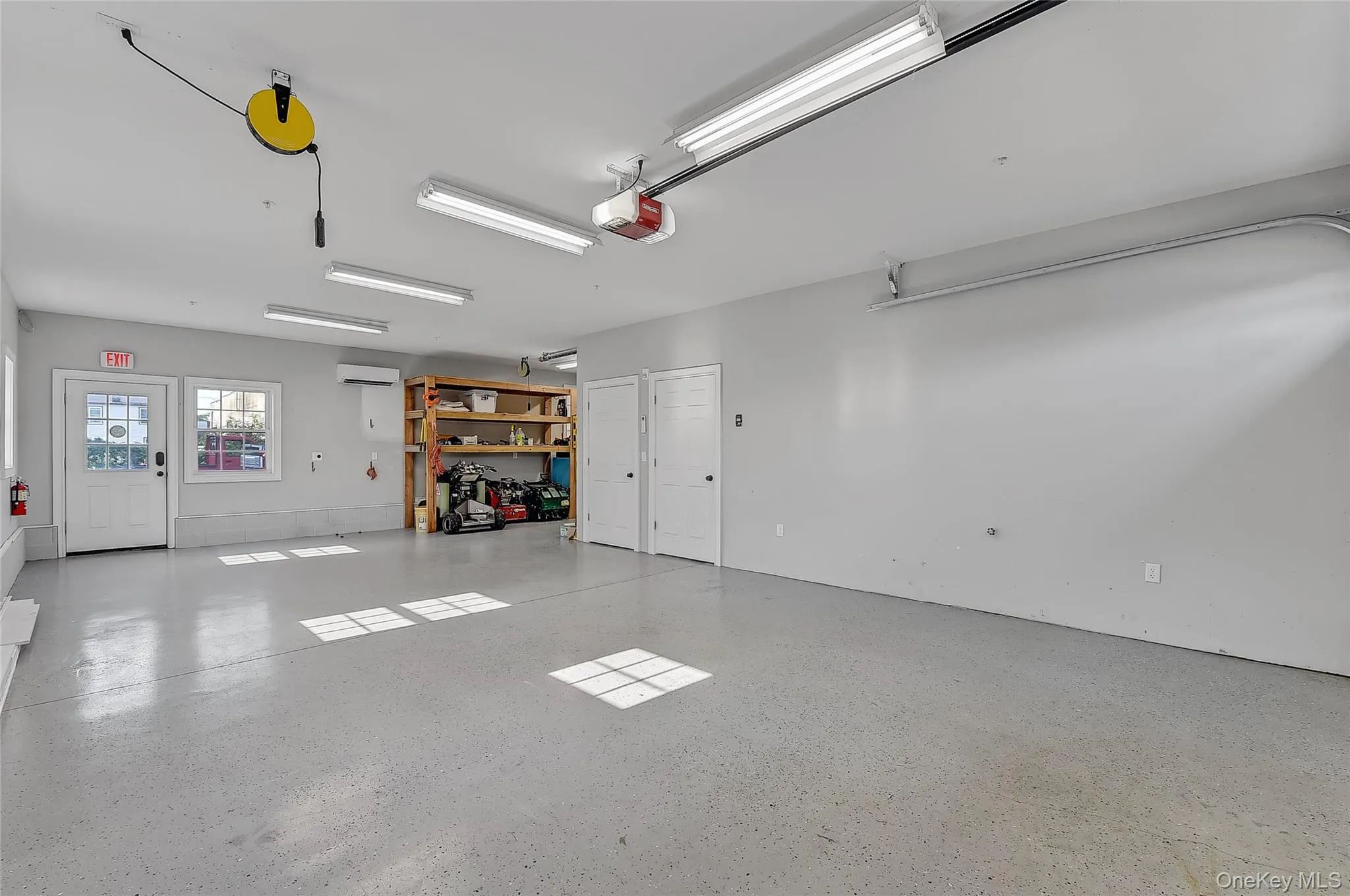 Garage featuring a wall mounted air conditioner and a garage door opener Garage featuring a wall mounted air conditioner and a garage door opener