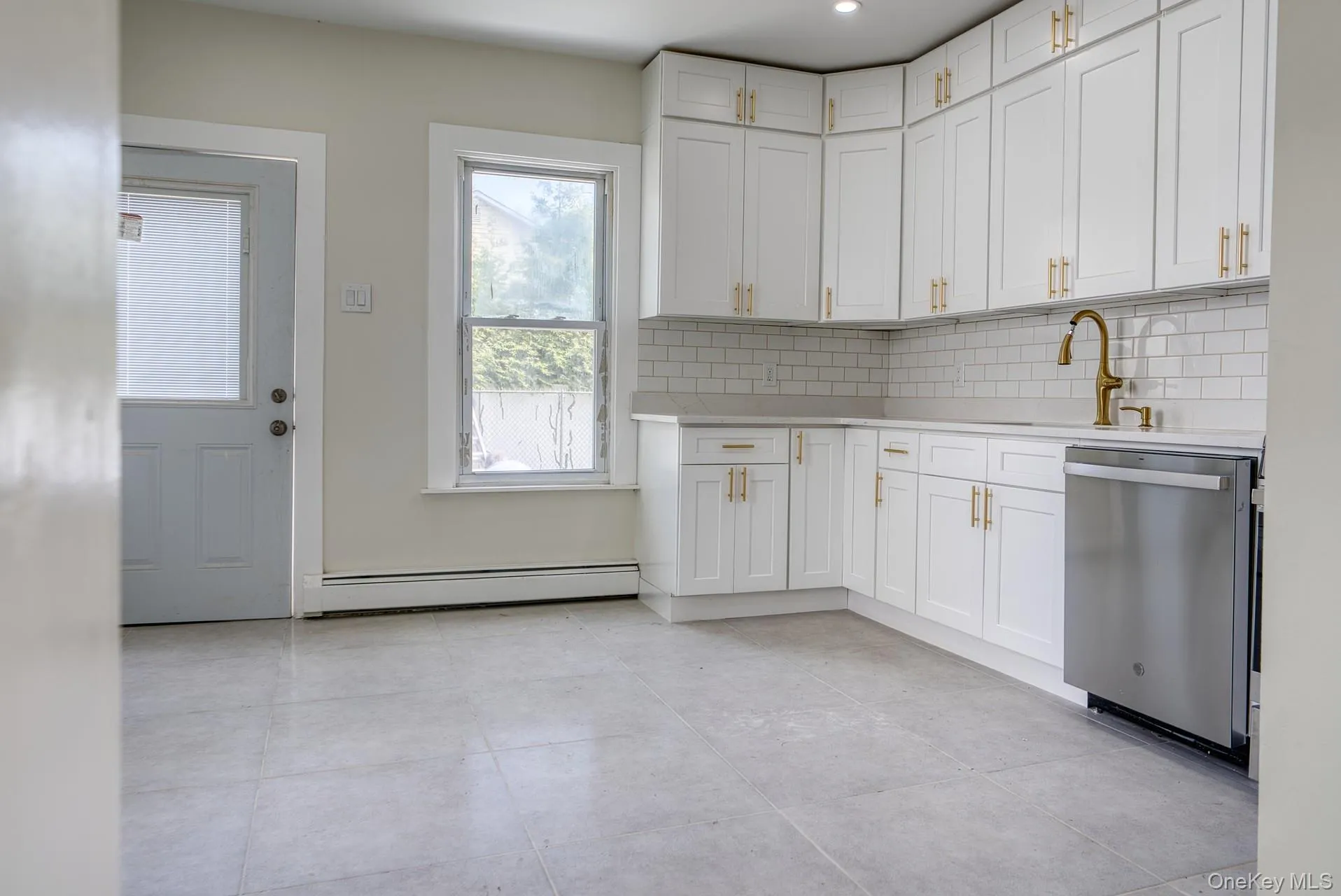 Kitchen with stainless steel dishwasher, a baseboard heating unit, light countertops, and tasteful backsplash Kitchen with stainless steel dishwasher, a baseboard heating unit, light countertops, and tasteful backsplash