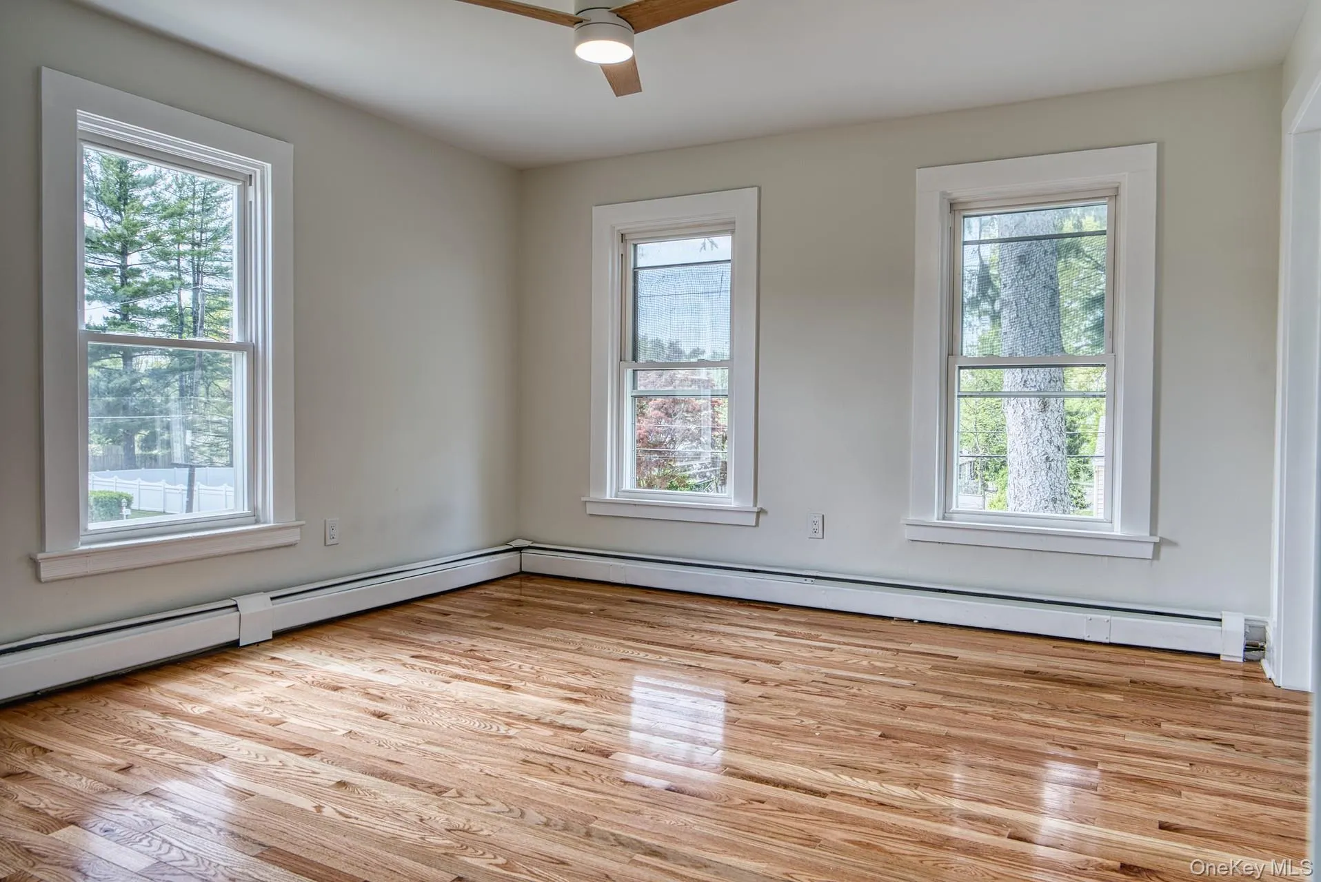 Unfurnished room featuring plenty of natural light, ceiling fan, and wood finished floors Unfurnished room featuring plenty of natural light, ceiling fan, and wood finished floors