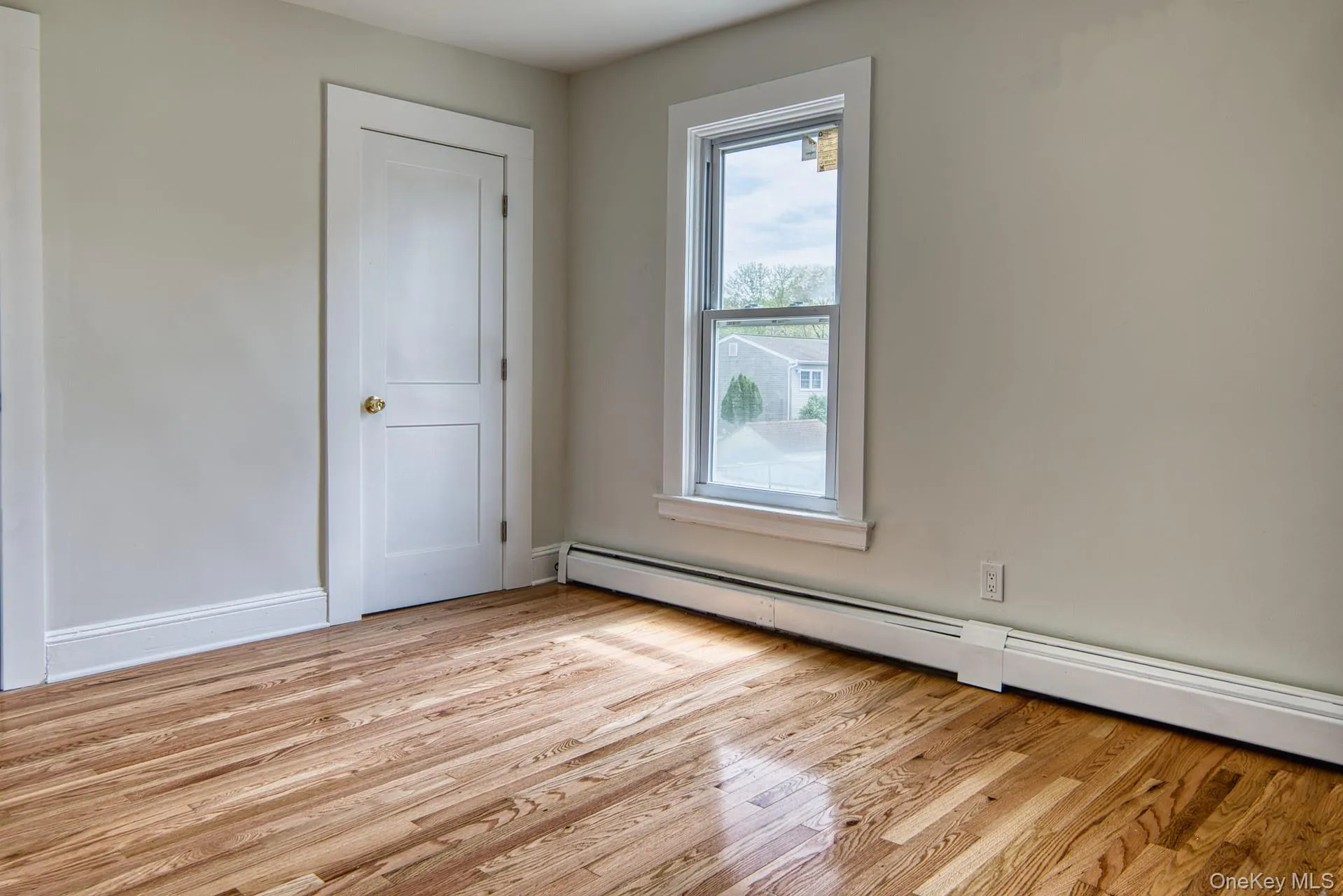 Spare room with a baseboard heating unit and light wood-style floors Spare room with a baseboard heating unit and light wood-style floors