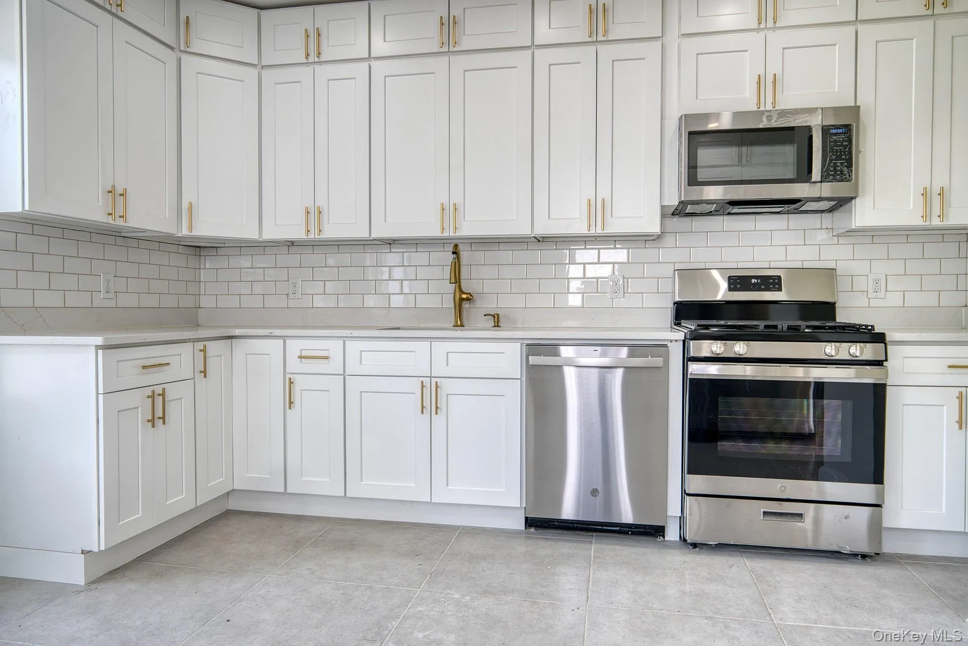 Kitchen featuring stainless steel appliances, a sink, light countertops, and decorative backsplash Kitchen featuring stainless steel appliances, a sink, light countertops, and decorative backsplash
