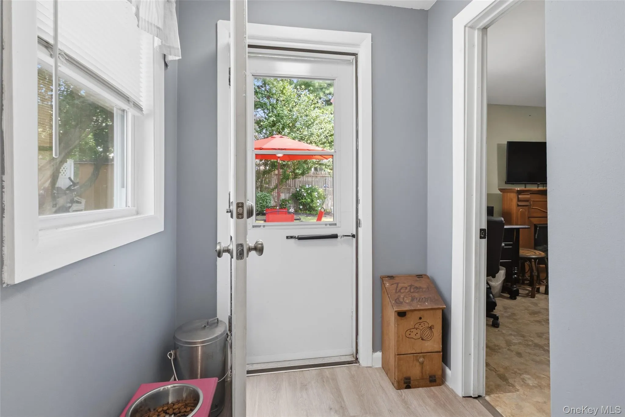 Entryway featuring a white door with transom window, light gray walls, and wood-finish flooring Entryway featuring a white door with transom window, light gray walls, and wood-finish flooring