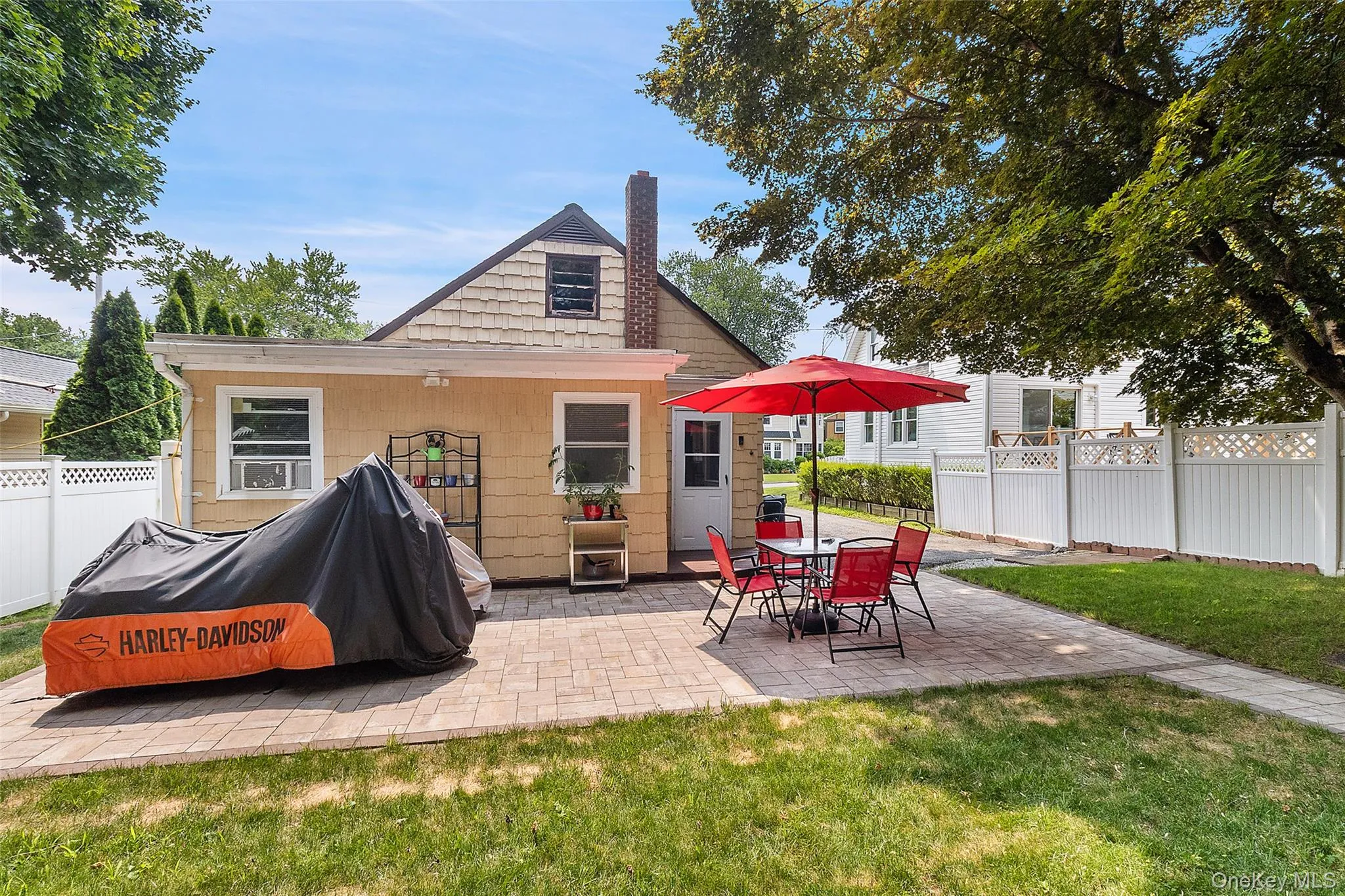Rear exterior featuring a paver patio, established lawn, and privacy fencing Rear exterior featuring a paver patio, established lawn, and privacy fencing