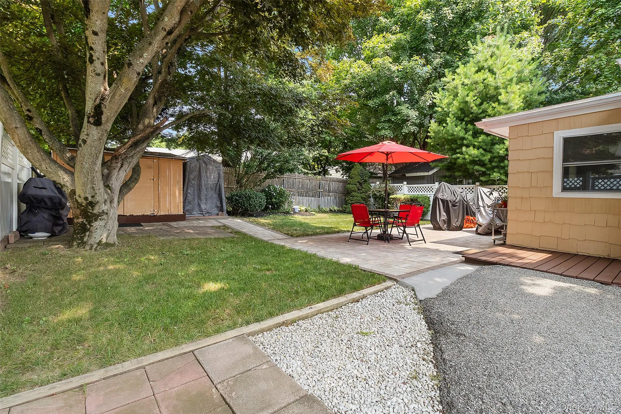 Expansive outdoor space featuring a paved patio, gravel area, and a grassy lawn Expansive outdoor space featuring a paved patio, gravel area, and a grassy lawn