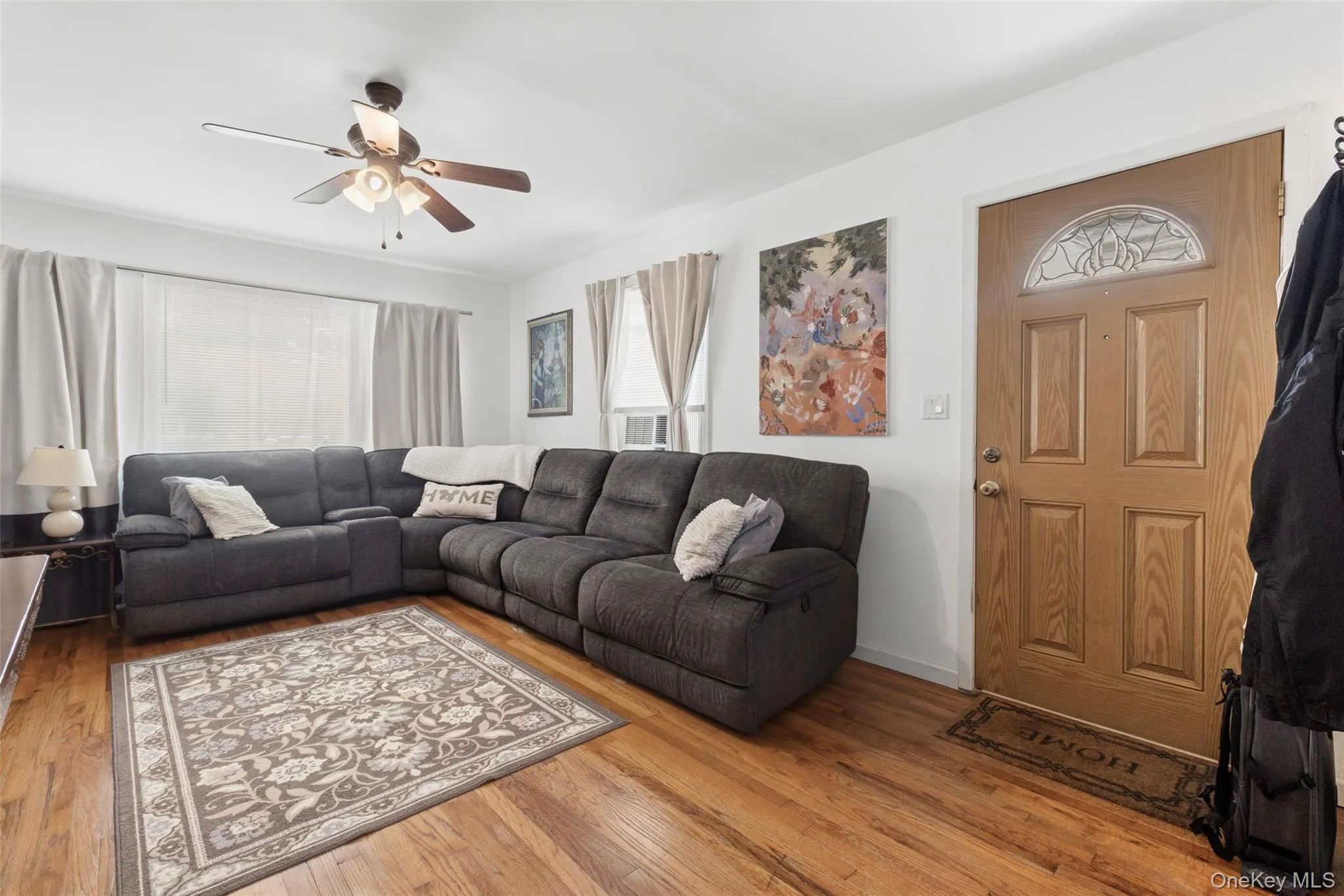 Entry area featuring wood-finish flooring, a paneled door with an arched decorative glass insert, and a ceiling fan with integrated lighting Entry area featuring wood-finish flooring, a paneled door with an arched decorative glass insert, and a ceiling fan with integrated lighting