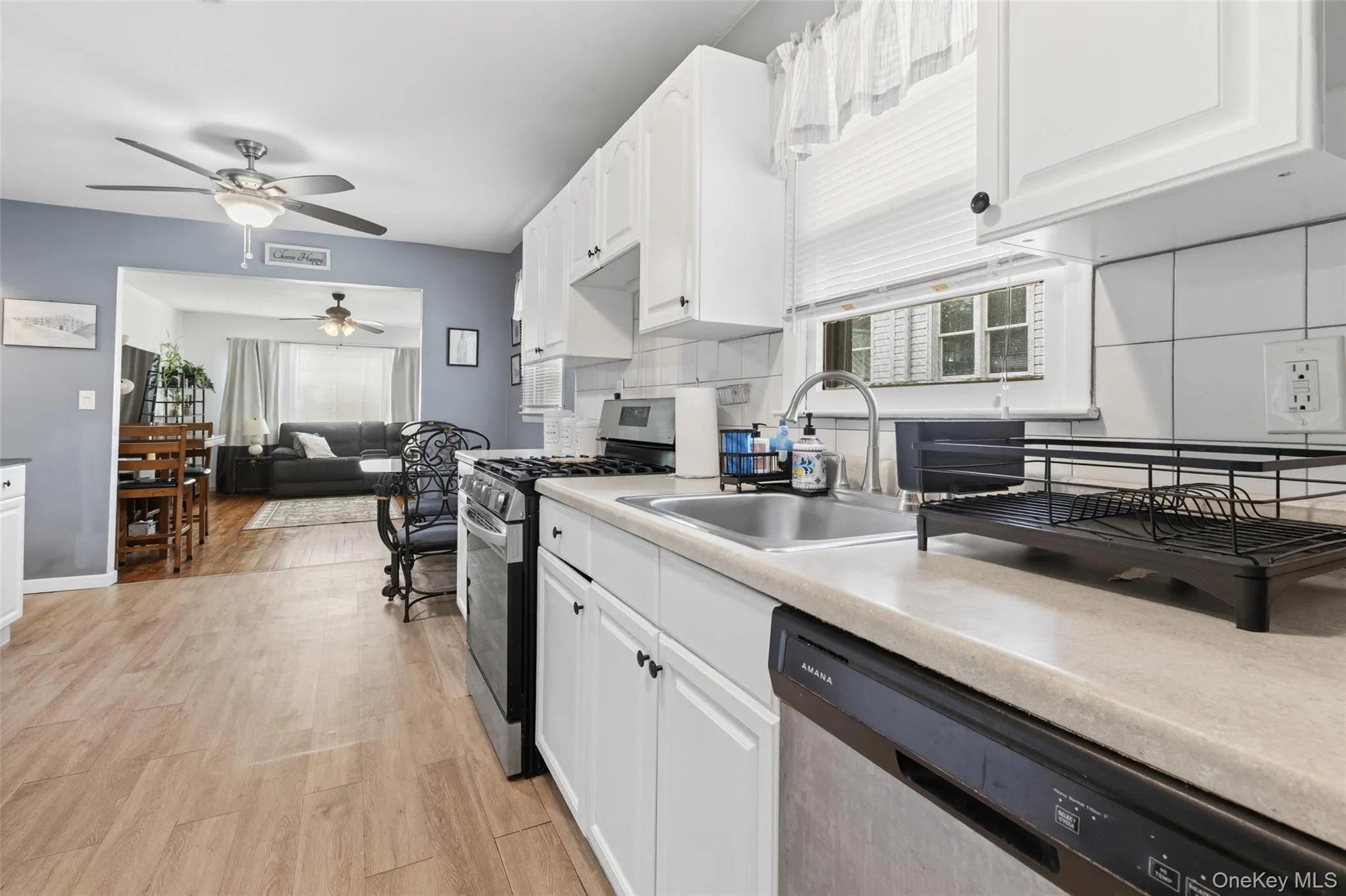 Kitchen featuring white cabinetry, a stainless steel sink, and light-toned countertops Kitchen featuring white cabinetry, a stainless steel sink, and light-toned countertops
