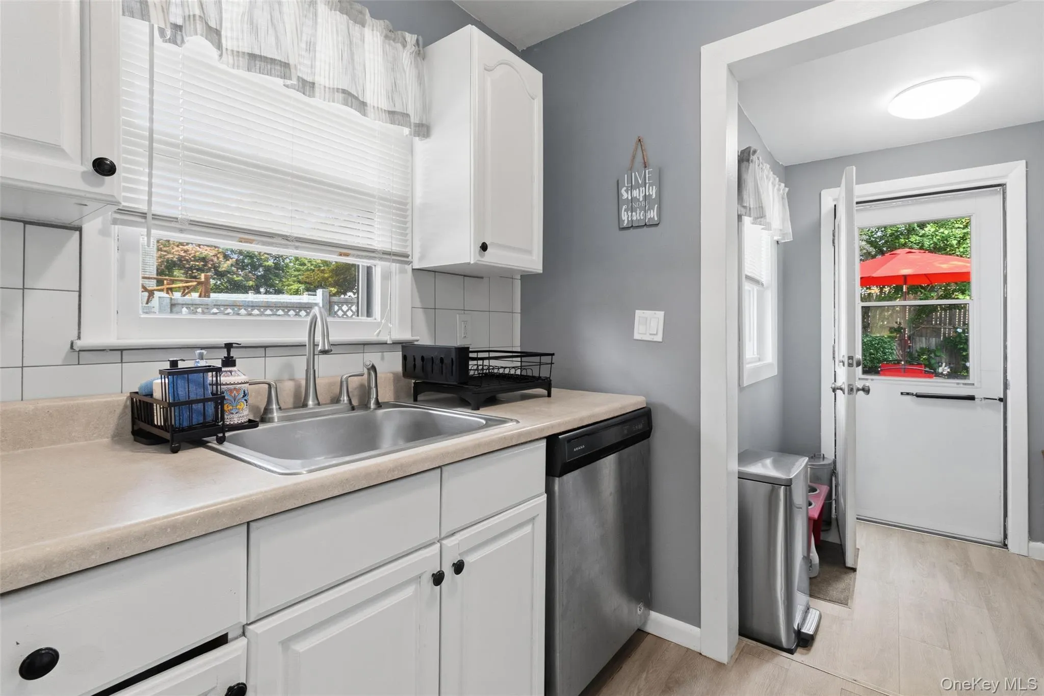 Kitchen area with white cabinetry, light countertops, and a stainless steel sink with a single-handle faucet Kitchen area with white cabinetry, light countertops, and a stainless steel sink with a single-handle faucet