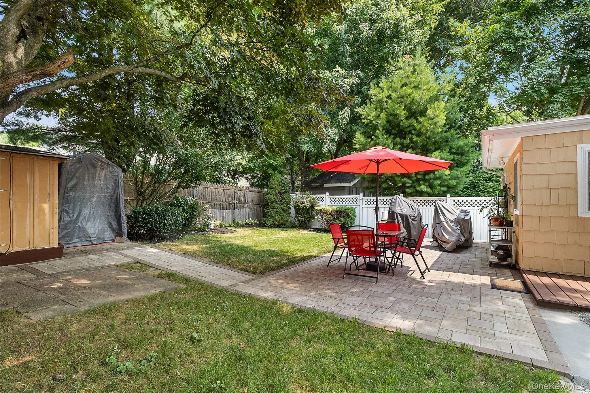 Expansive backyard featuring a paver patio, separate concrete slab, and a manicured lawn Expansive backyard featuring a paver patio, separate concrete slab, and a manicured lawn