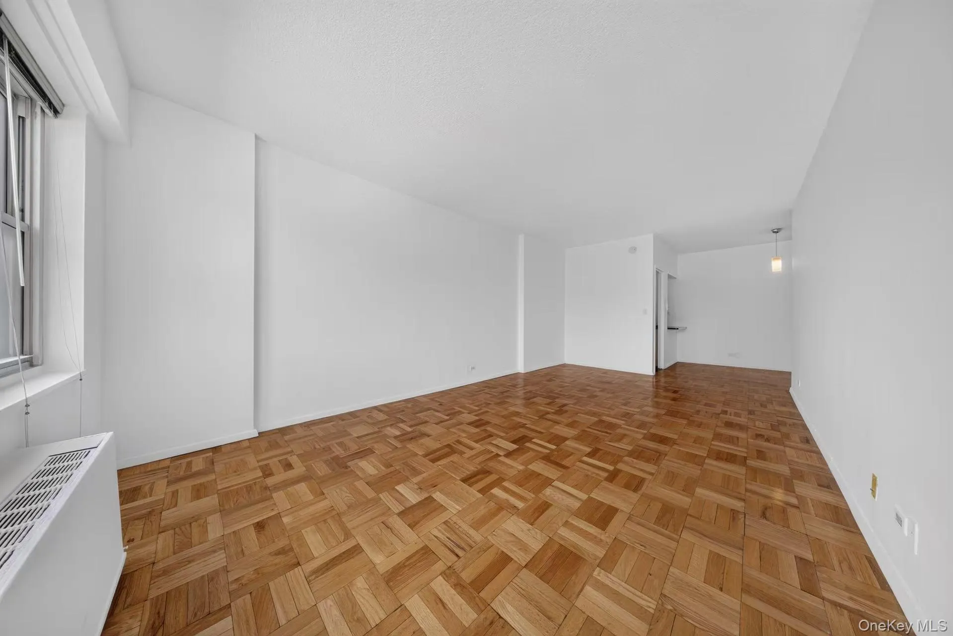 Expansive living space featuring parquet wood flooring and crisp white walls Expansive living space featuring parquet wood flooring and crisp white walls