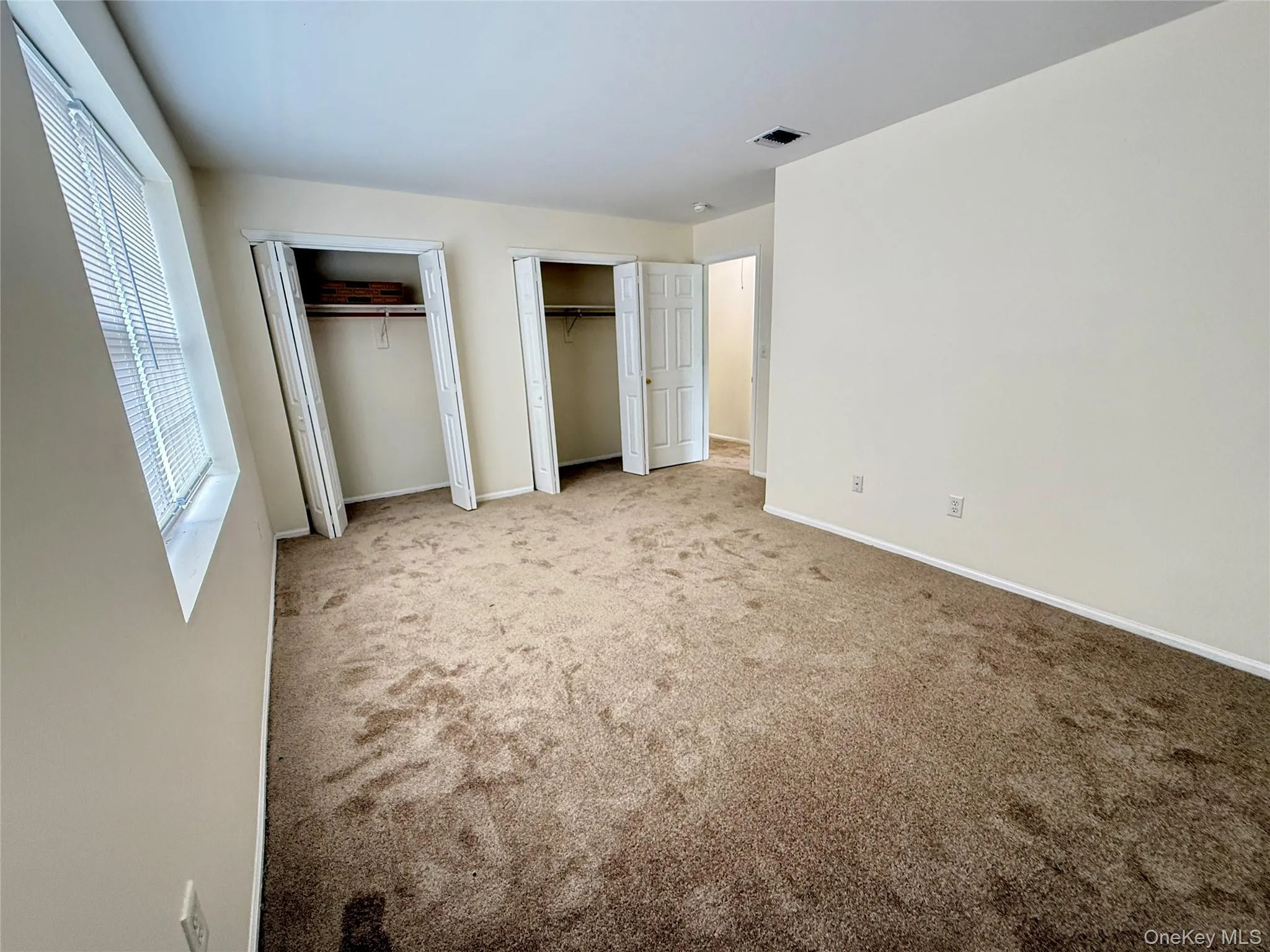 Soft pile carpeting, neutral wall tones, window with horizontal blinds, and ample closet space Soft pile carpeting, neutral wall tones, window with horizontal blinds, and ample closet space