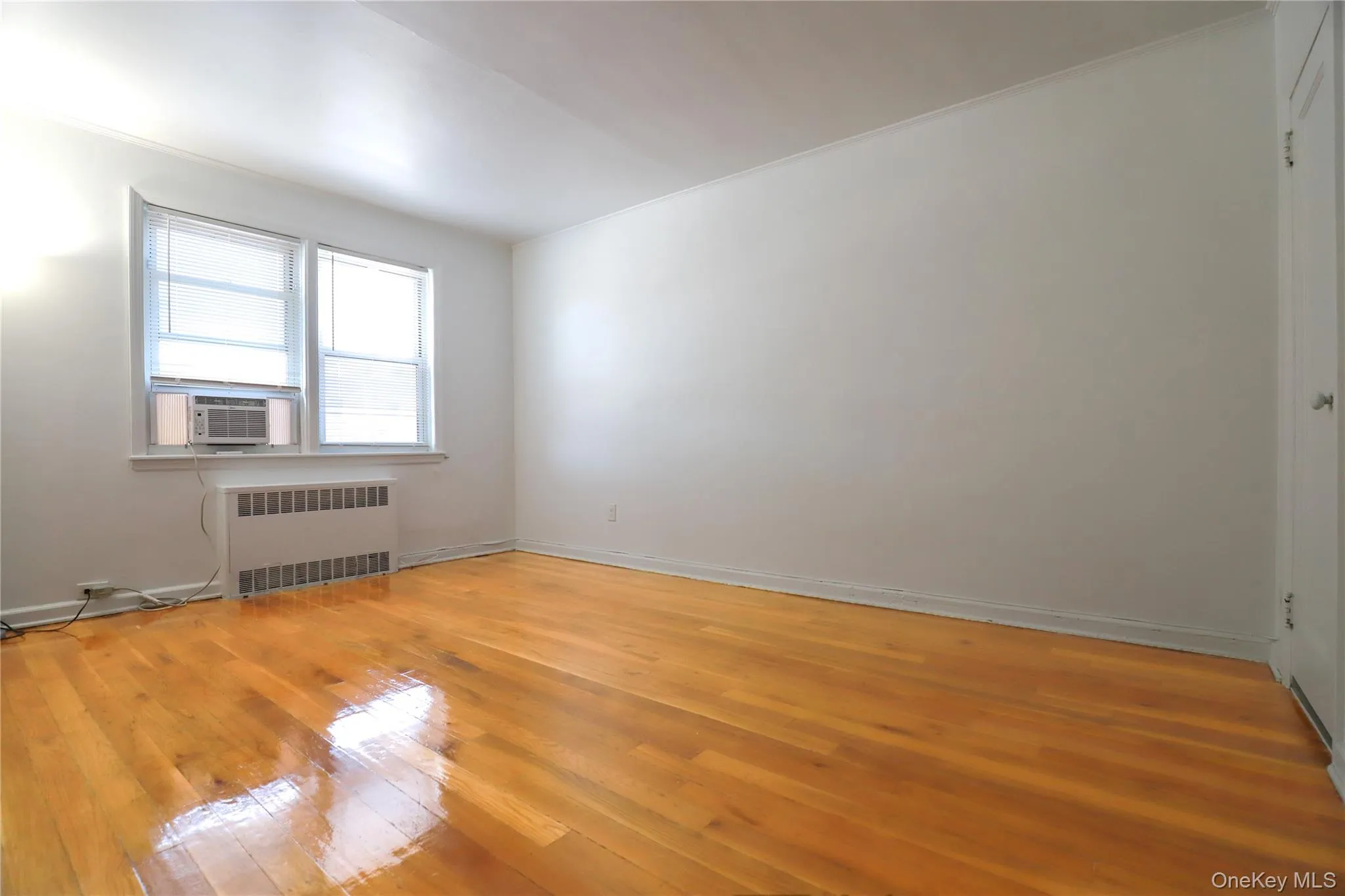 Bright and spacious primary bedroom with hardwood floors, generous natural light, and built-in closets Bright and spacious primary bedroom with hardwood floors, generous natural light, and built-in closets