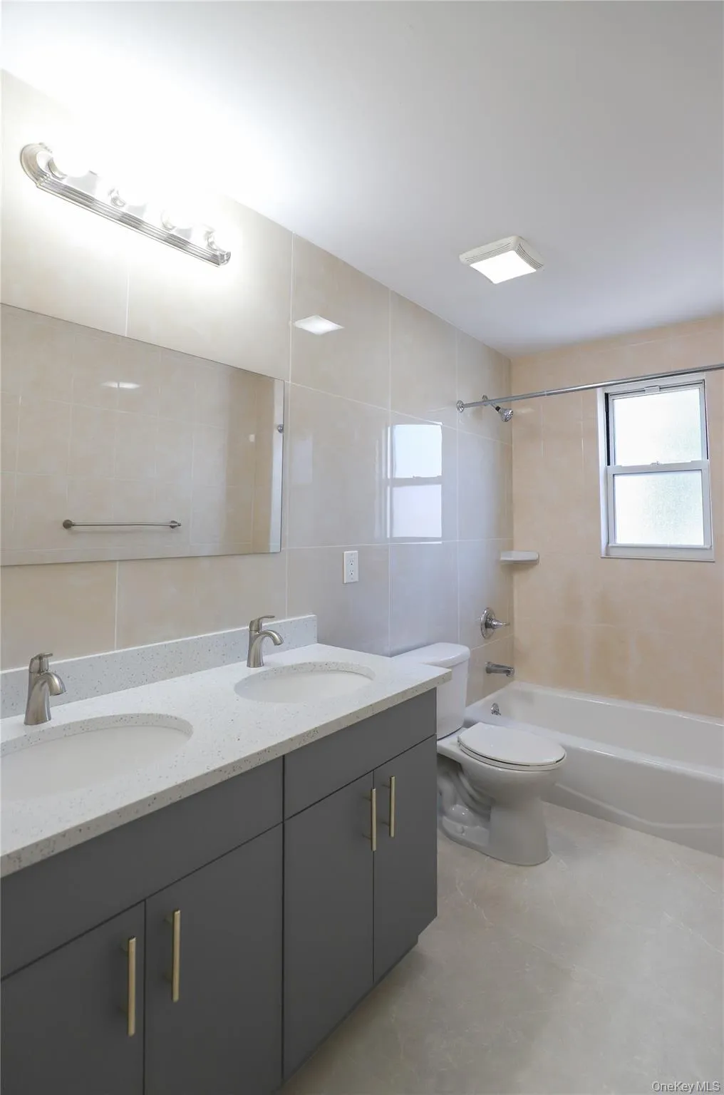 Dual vanity bathroom featuring a white countertop and gray cabinetry with gold-tone hardware Dual vanity bathroom featuring a white countertop and gray cabinetry with gold-tone hardware