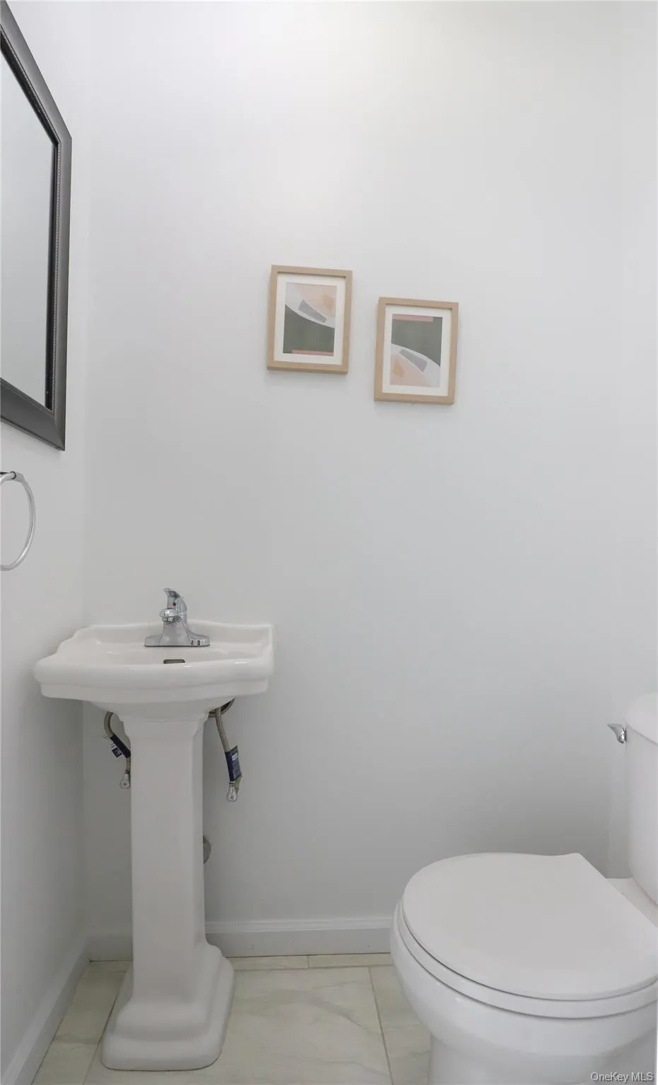 Half bathroom featuring white pedestal sink with chrome faucet, white toilet, and light-toned tile flooring Half bathroom featuring white pedestal sink with chrome faucet, white toilet, and light-toned tile flooring