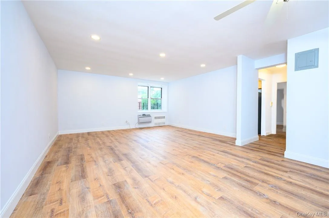 Spare room featuring ceiling fan, an AC wall unit, and light wood-type flooring Spare room featuring ceiling fan, an AC wall unit, and light wood-type flooring